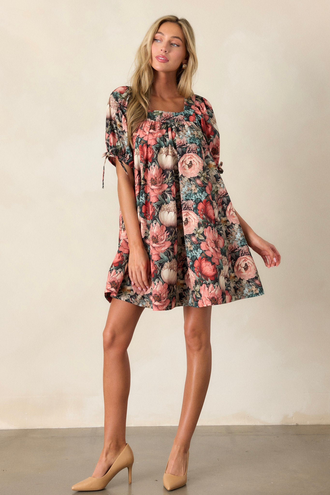 Action shot of a black floral dress displaying the flow and movement, highlighting the square neckline, puff sleeves, and two functional side pockets.