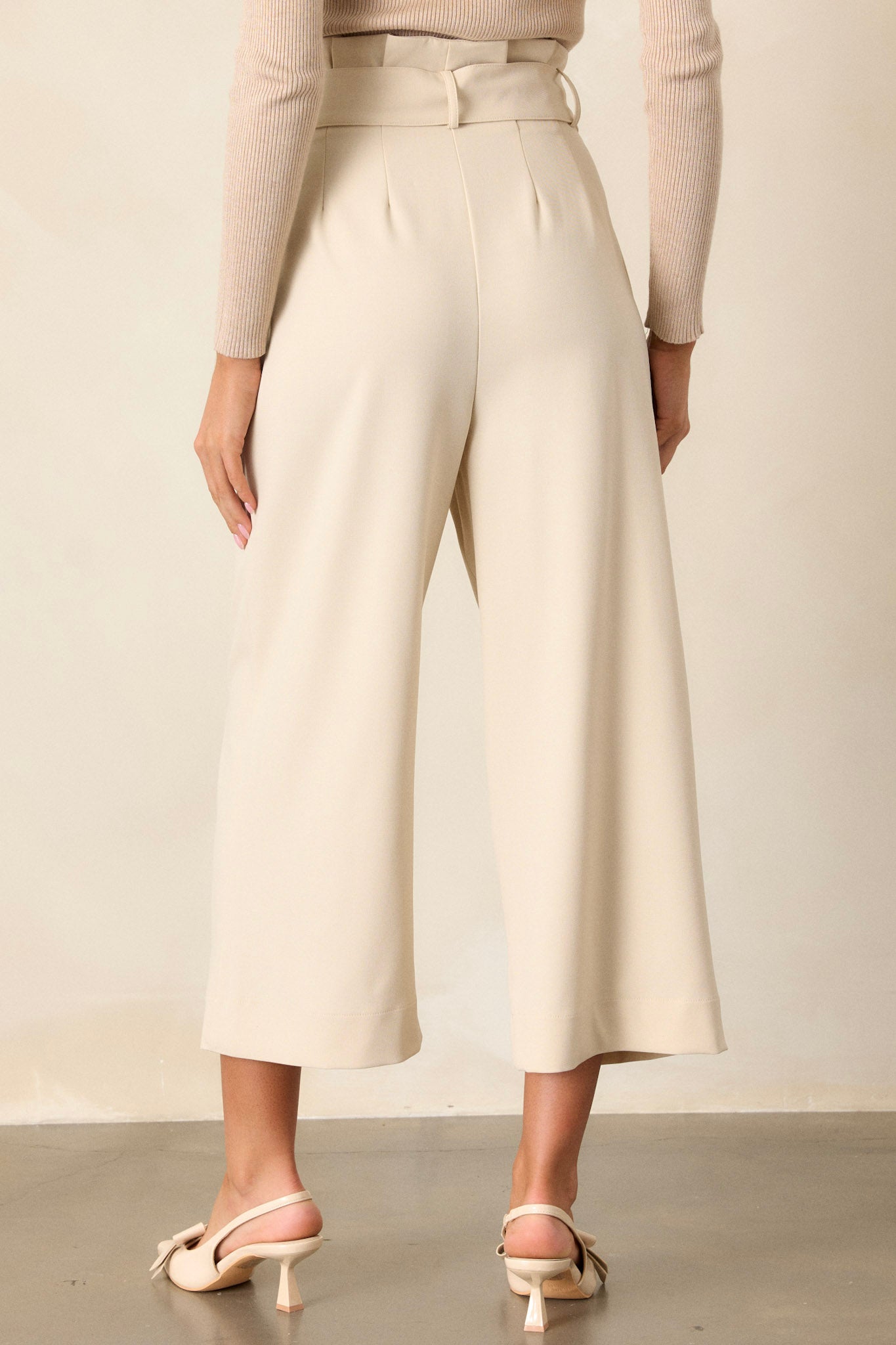 Back view of the oatmeal pants highlighting the belt loops and the way the functional belt cinches the waist, creating a streamlined silhouette