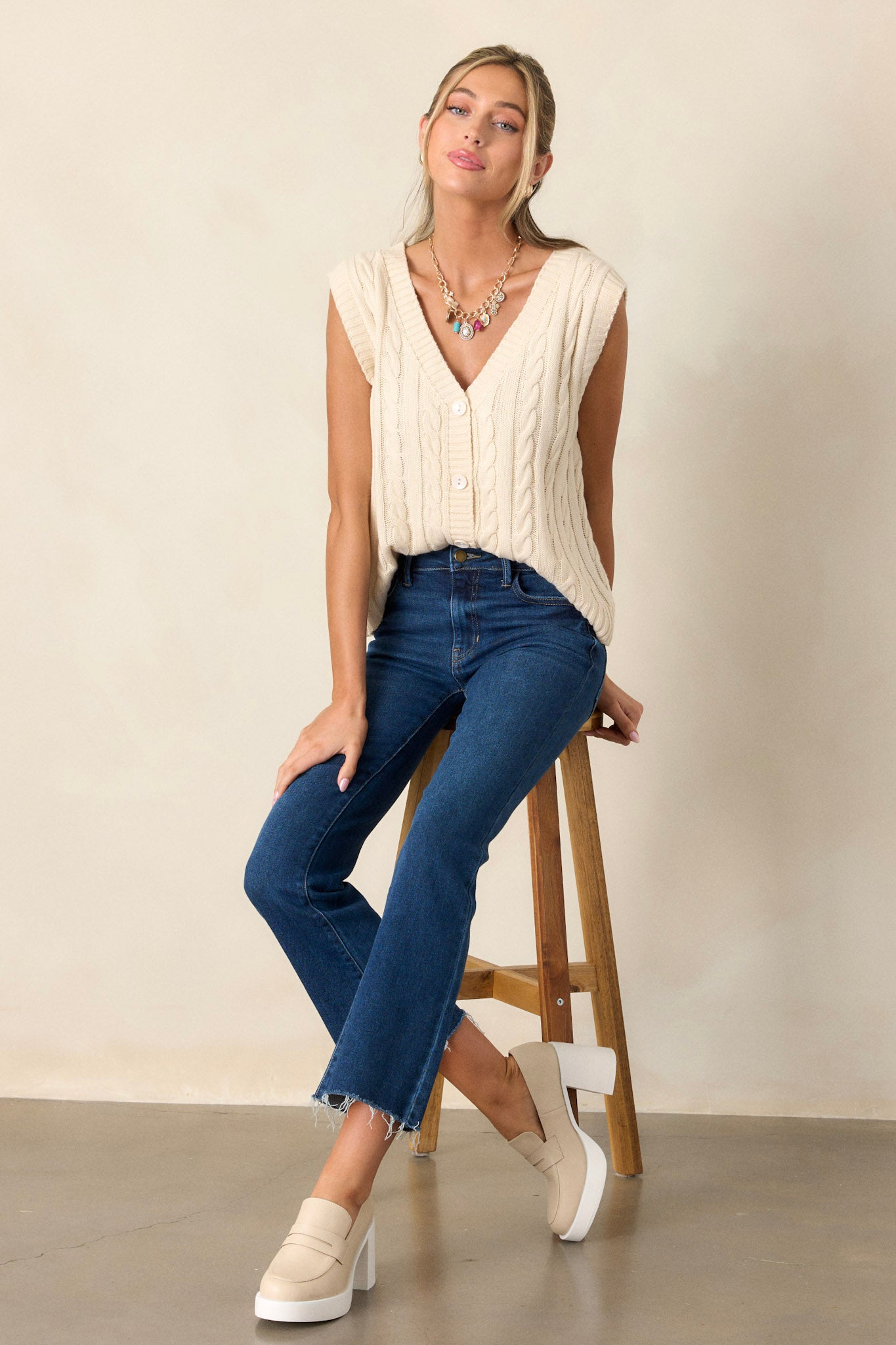 Full length view of a model wearing the sweater vest featuring a v-neckline, a cable-knit design, and a ribbed waistline, providing a versatile layering piece.