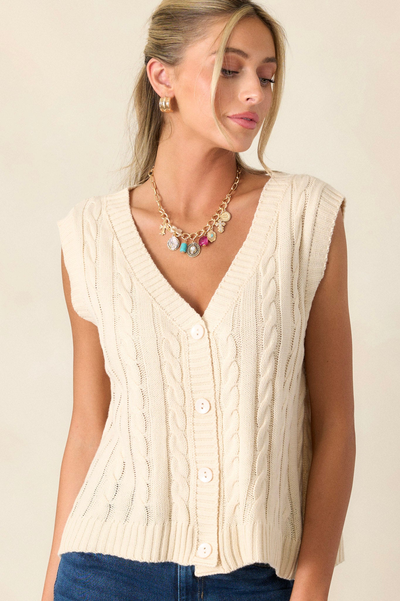 Front angled view of the sweater vest featuring a v-neckline, cable-knit design, and ribbed waistline