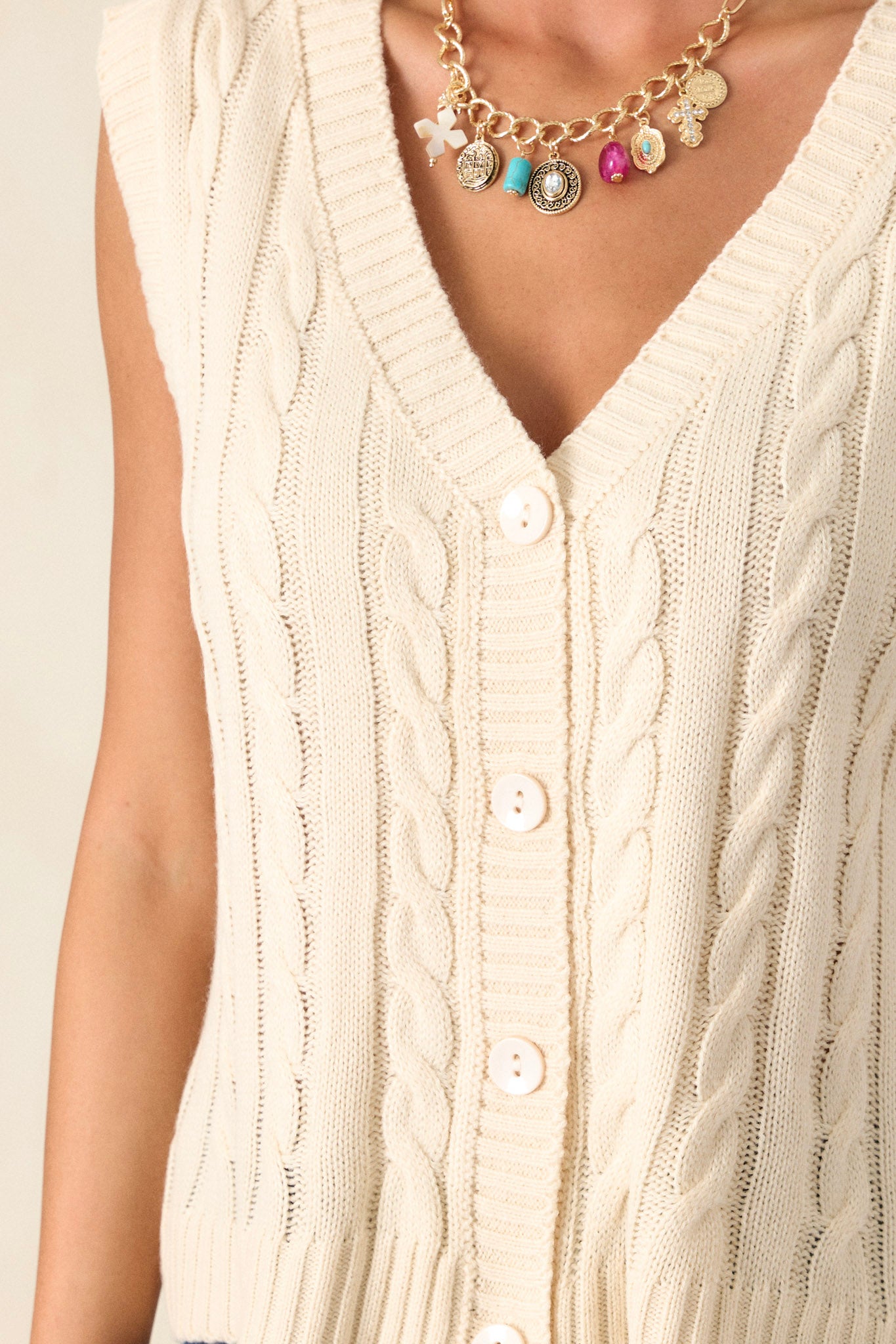 Close-up of the sweater vest focusing on the intricate cable-knit design, the v-neckline, and the ribbed waistline, revealing the texture and craftsmanship.