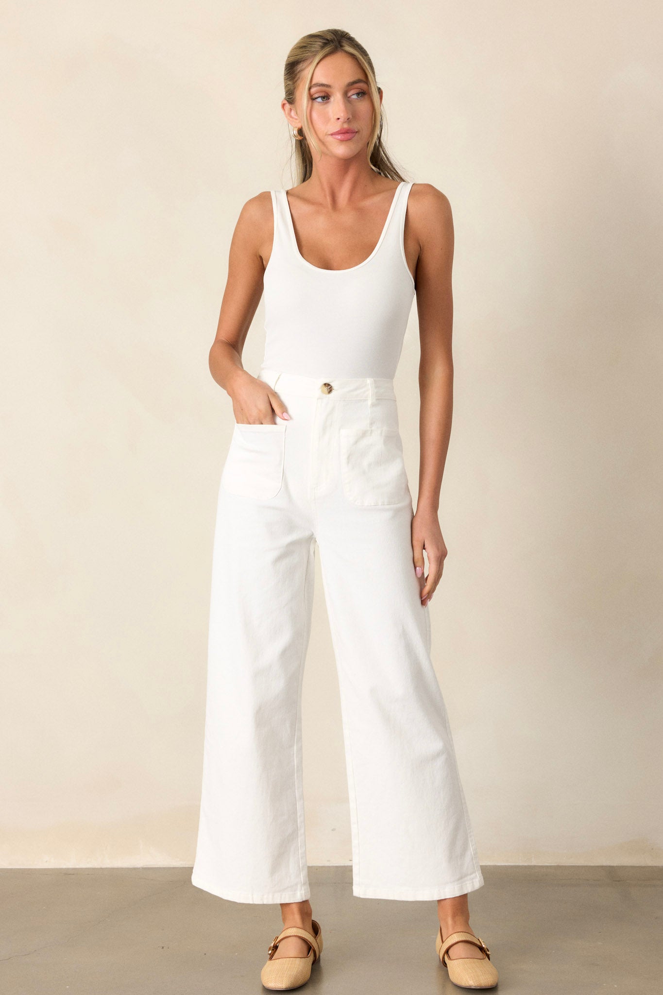 Full length view of a white bodysuit featuring thick straps, a double scoop neckline, and a thonged bottom