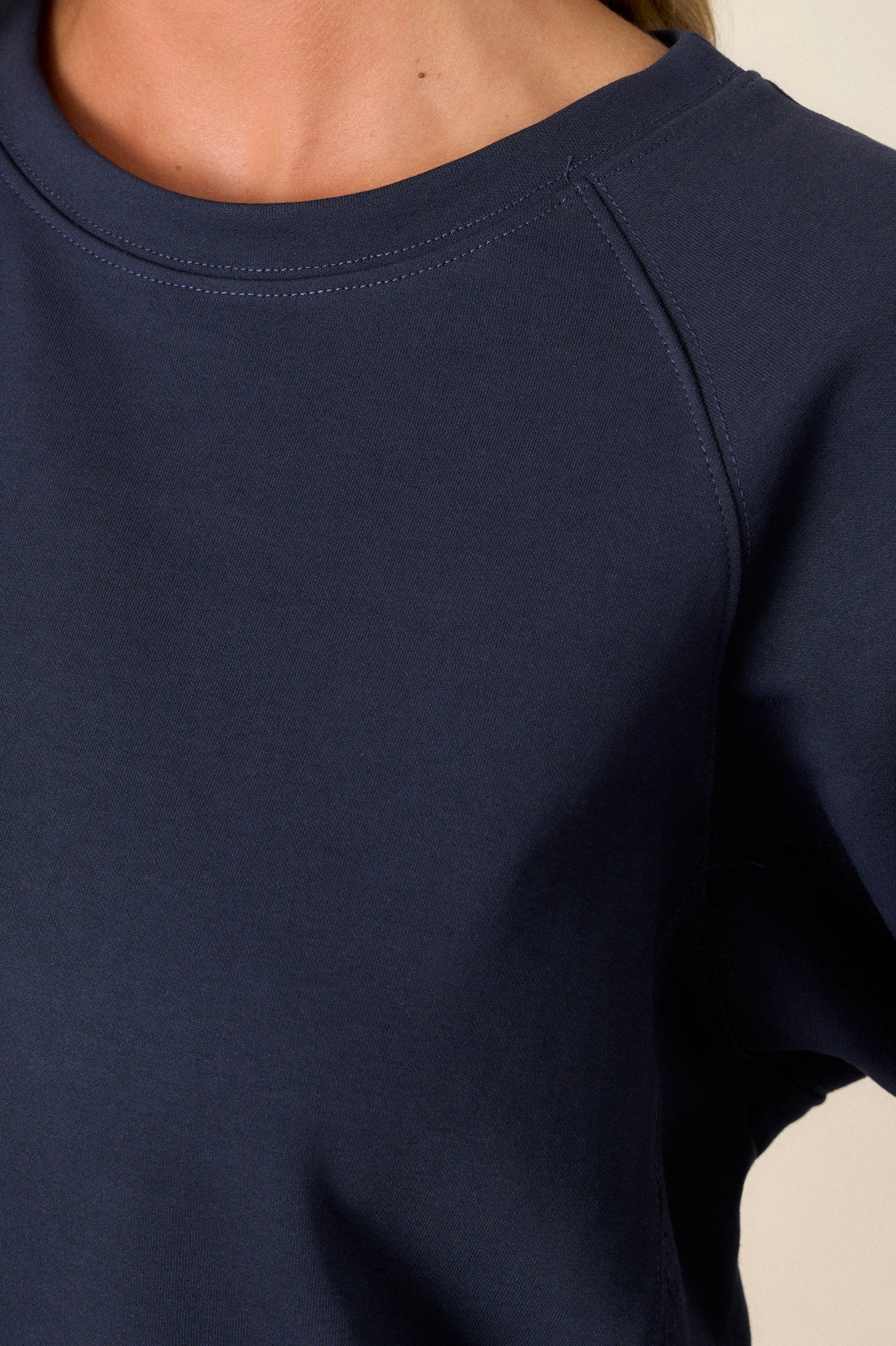 Close-up of the top focusing on the crew neckline, the texture of the soft fabric, and the fine stitch detailing around the hem.