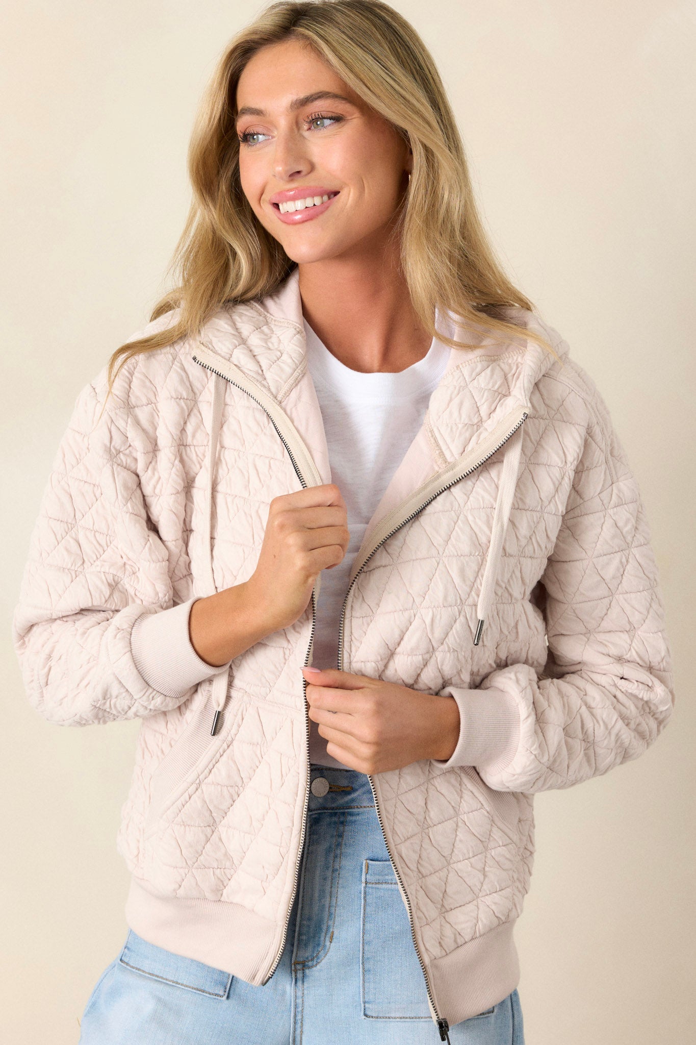 Action shot of the ivory quilted jacket displaying the structure and movement, highlighting the high neckline, quilted design, and thick hem with cuffed long sleeves.