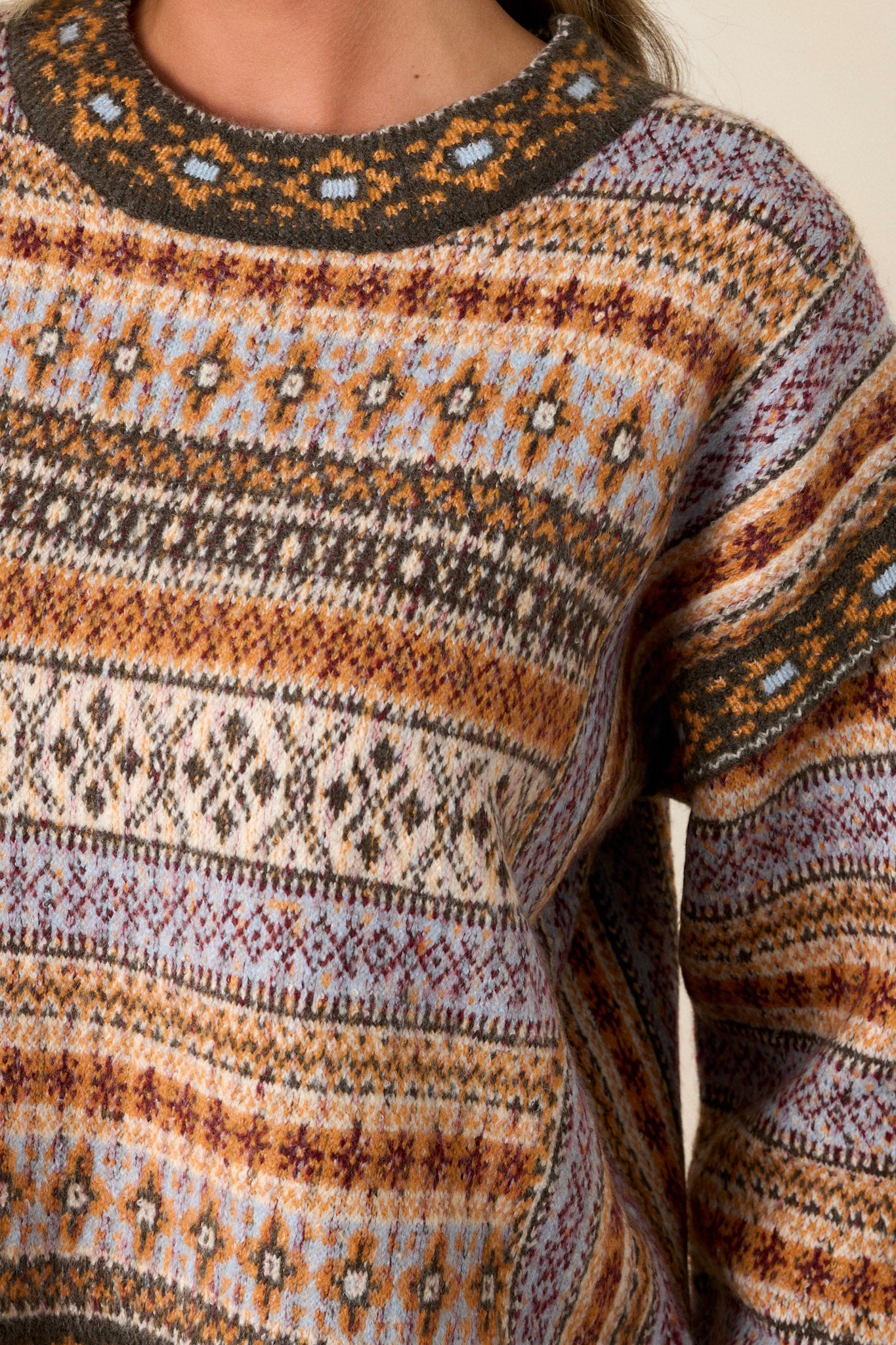 Close-up of the sweater focusing on the scoop neckline, slight mock-neck, raw hems, and the texture of the fabric.