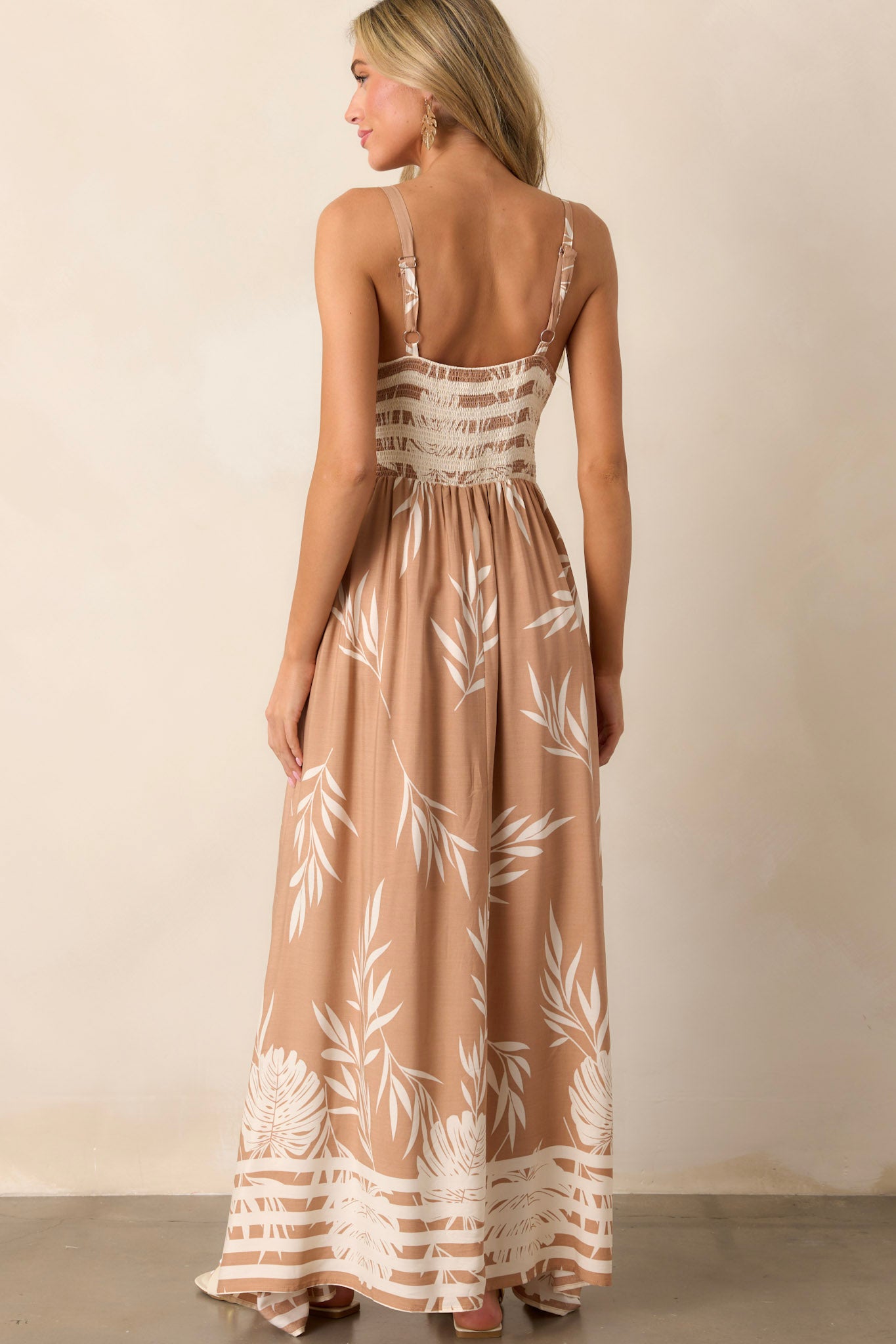 Back view of the tan dress highlighting the smocked back and the stripe detailing along the bottom.