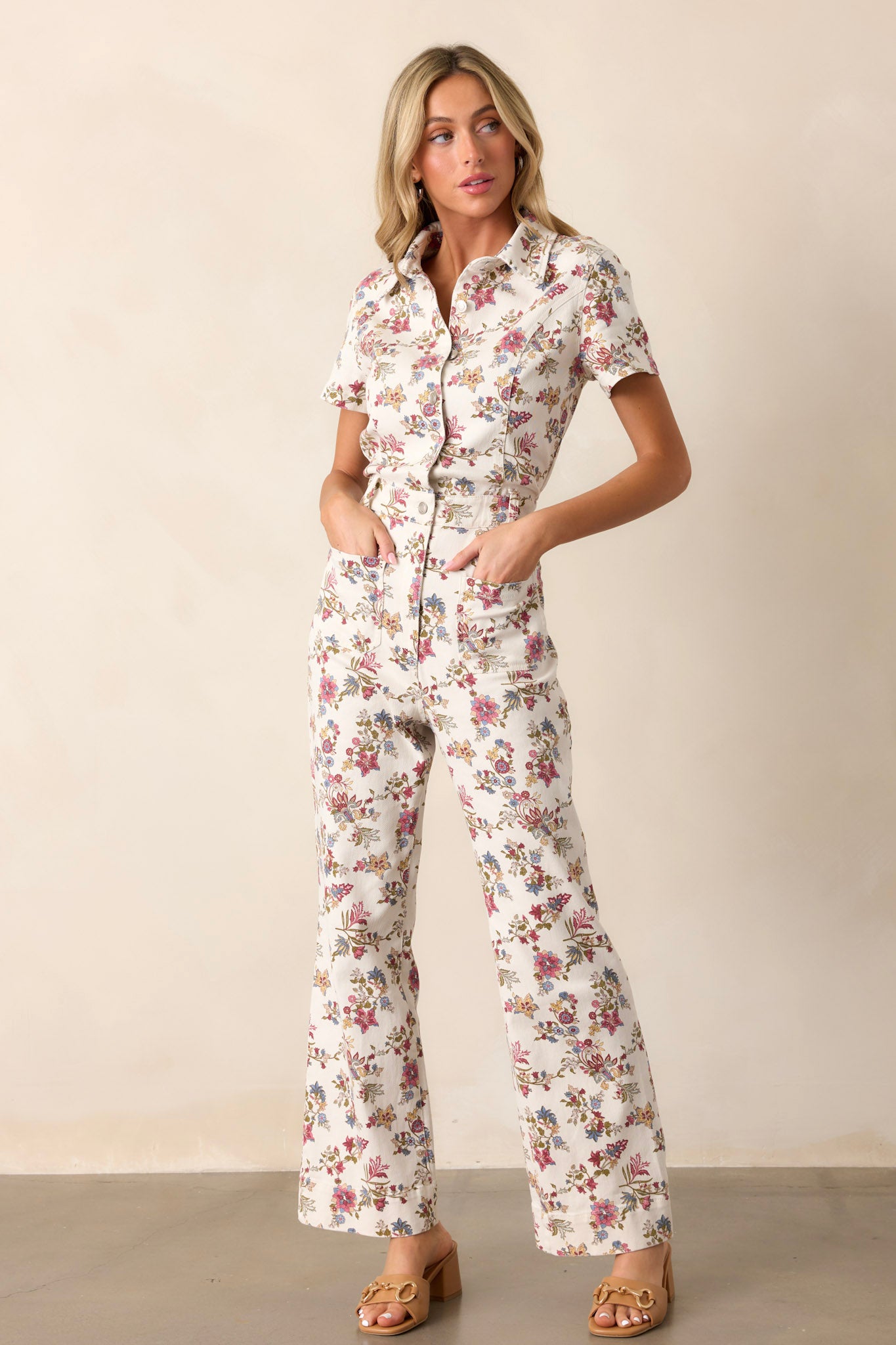 Full length view of a model wearing the jumpsuit featuring four functional pockets, a functional zipper, a collar, and a button-front top, showing the overall fit and structure.