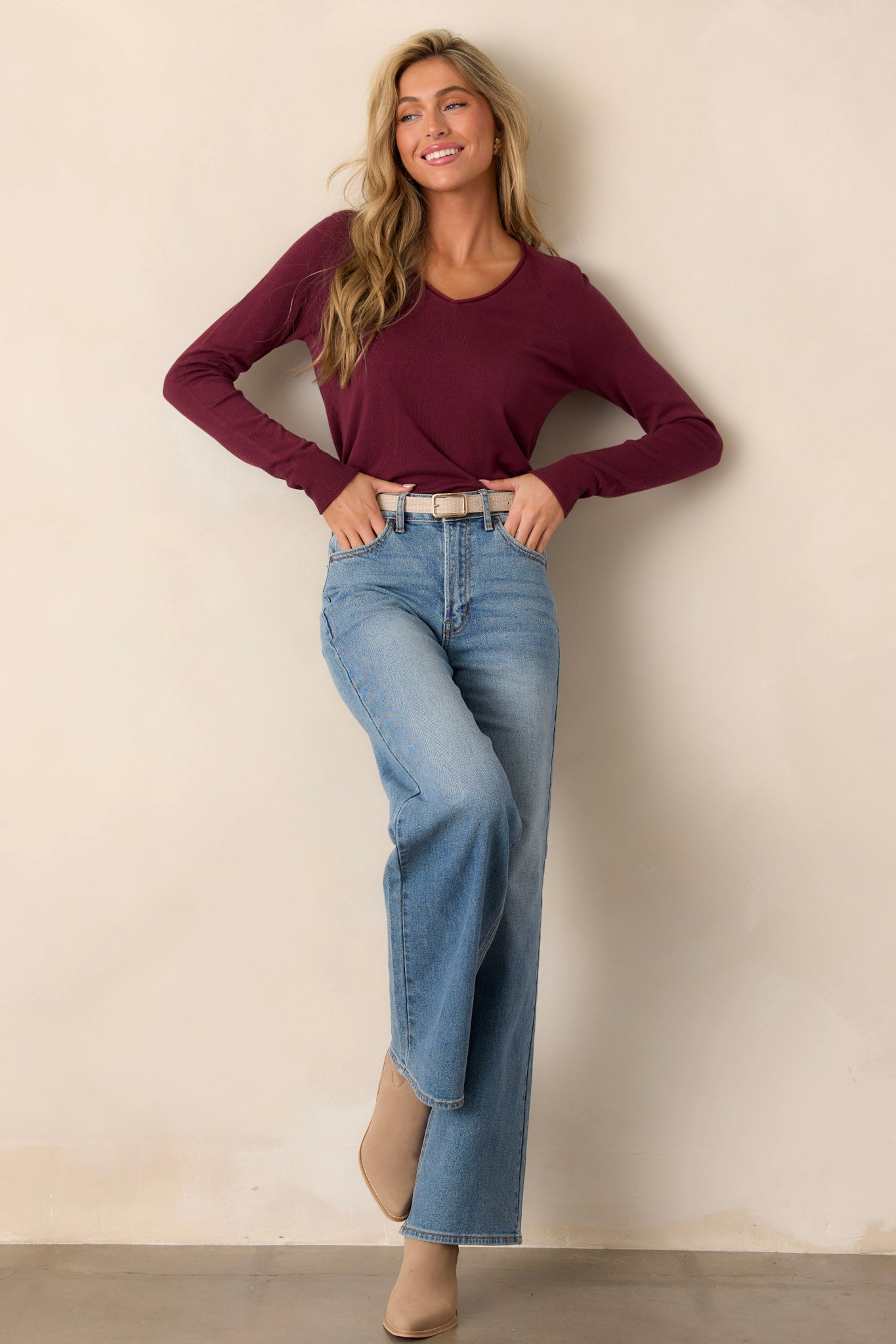 Casual knit top featuring a slight v-neck with raw edges, long cuffed sleeves, and small side slits at the hem.