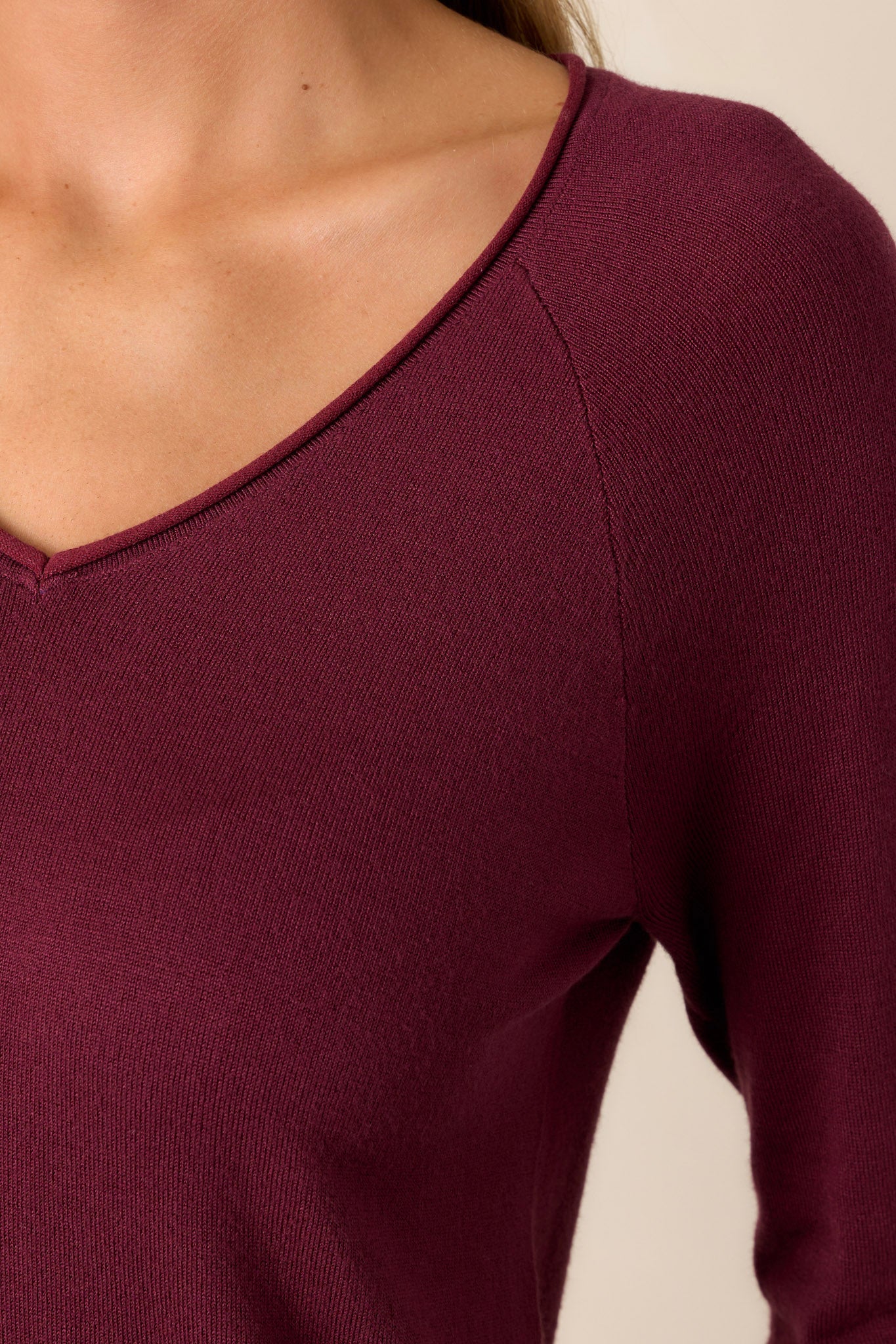 Close-up of the raw hemline on the slight v-neckline, emphasizing soft knit fabric texture.