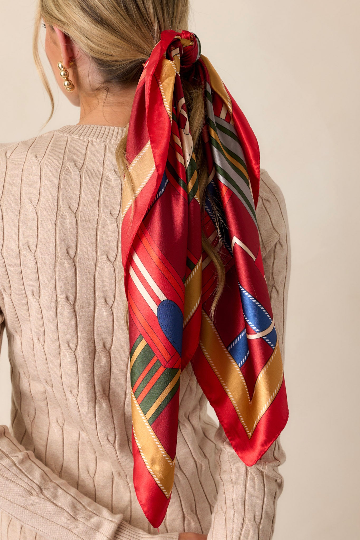 Close-up of this red scarf that features a satin material, and a multicolored print.