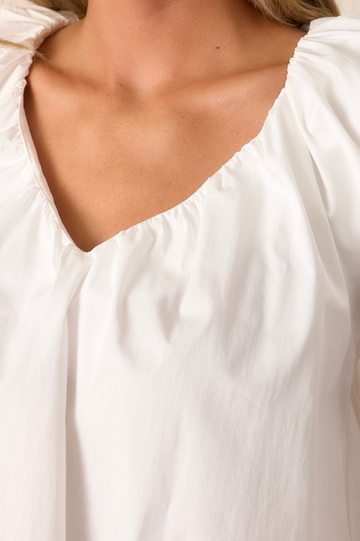 Close-up of the white top focusing on the v-neckline and the delicate flutter sleeves