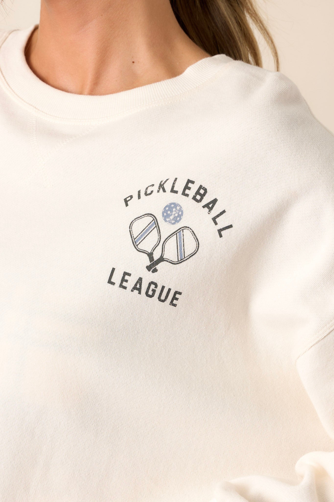 Close-up of the sweatshirt focusing on the crew neckline, the stripe detail on the cuffs, and the vibrant pickleball graphic.