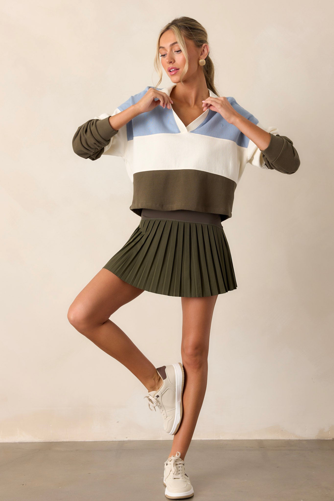 Action shot of the green skirt displaying the flow and movement of the pleats, emphasizing the high rise fit, elastic waistband, and the hidden built-in shorts.