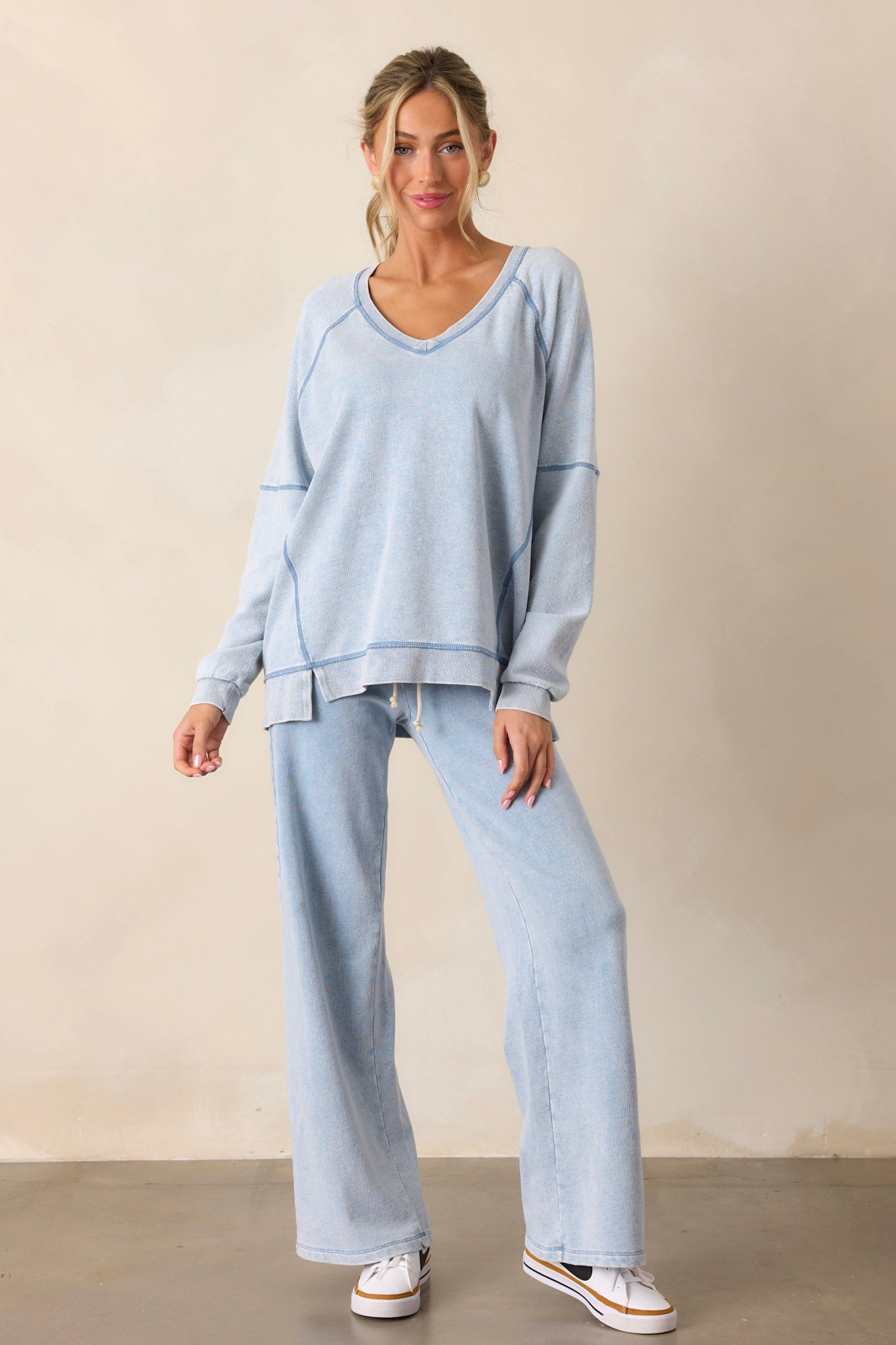 Front view of an indigo sweatshirt featuring a v-neckline, a soft knit texture, side slits in the hemline, and long sleeves