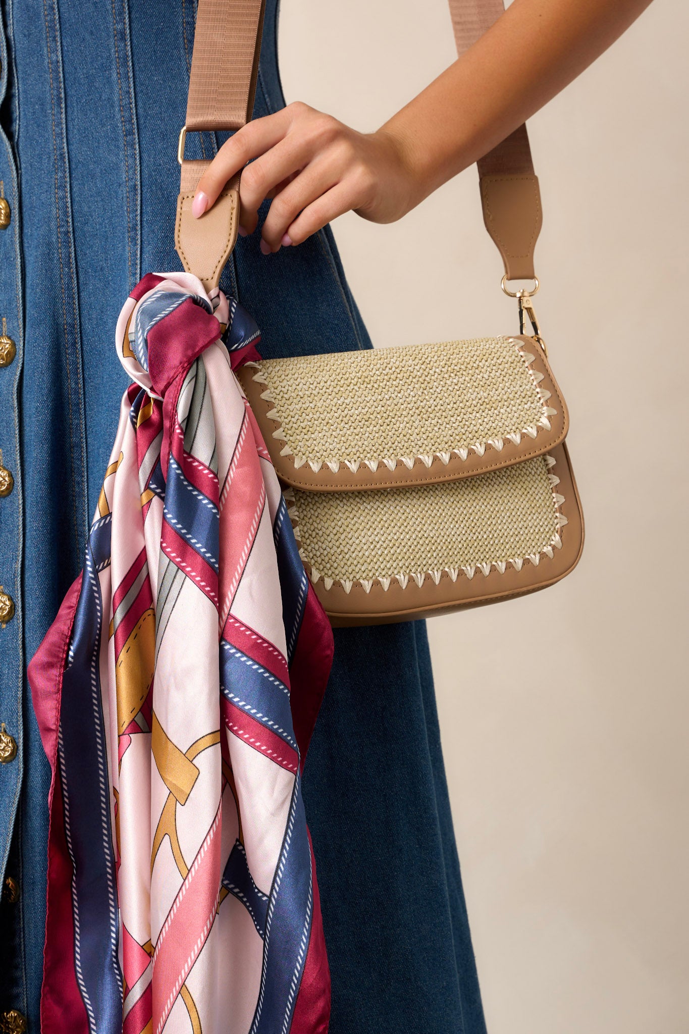 Side view of this tan woven handbag featuring a magnetic flap closure, two inside pockets, gold hardware, and an optional crossbody strap.