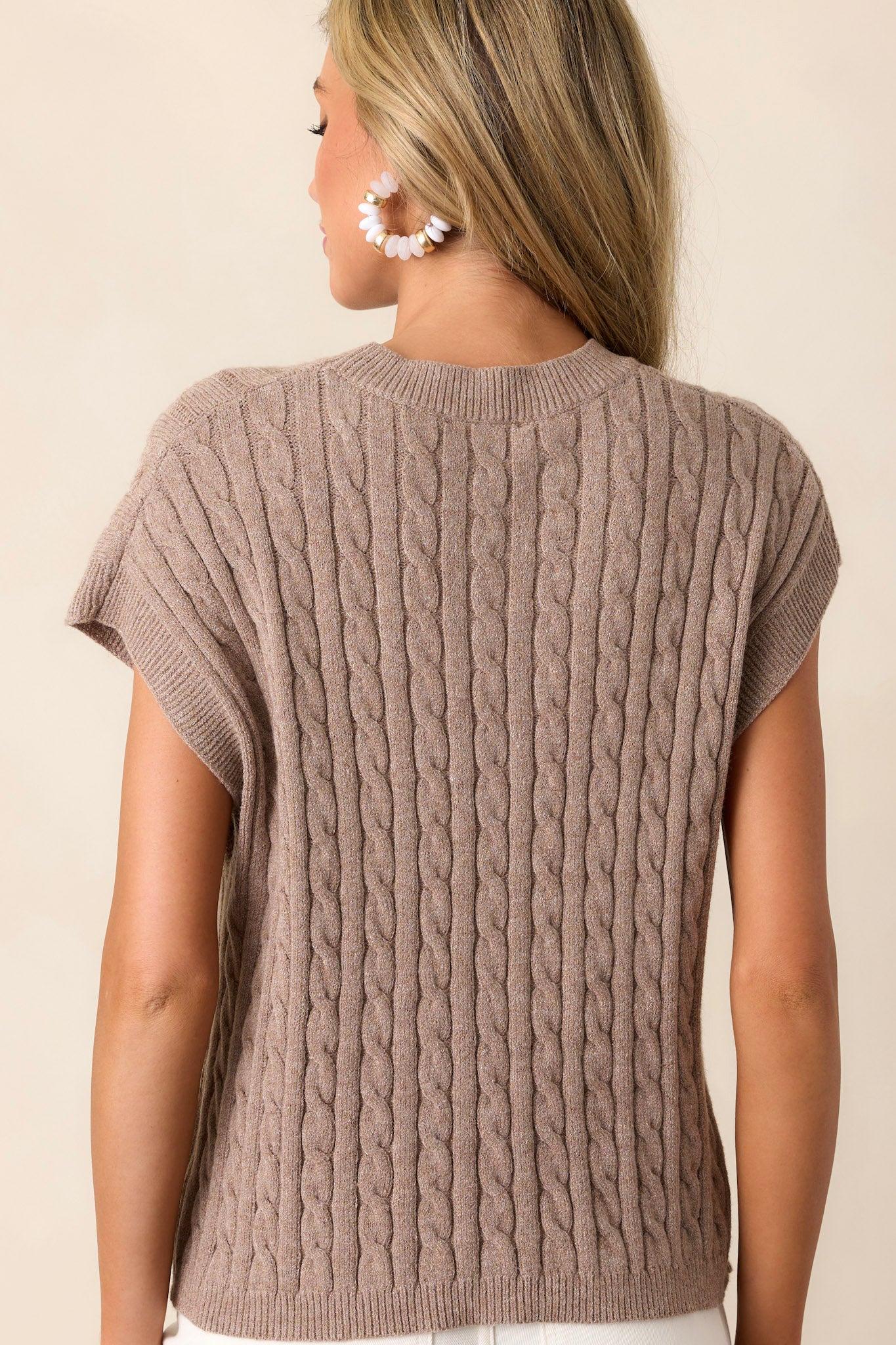 Back view of the taupe top showing the continuation of the cable-knit design and the fit of the ribbed neckline, with a clear view of the short cap sleeves