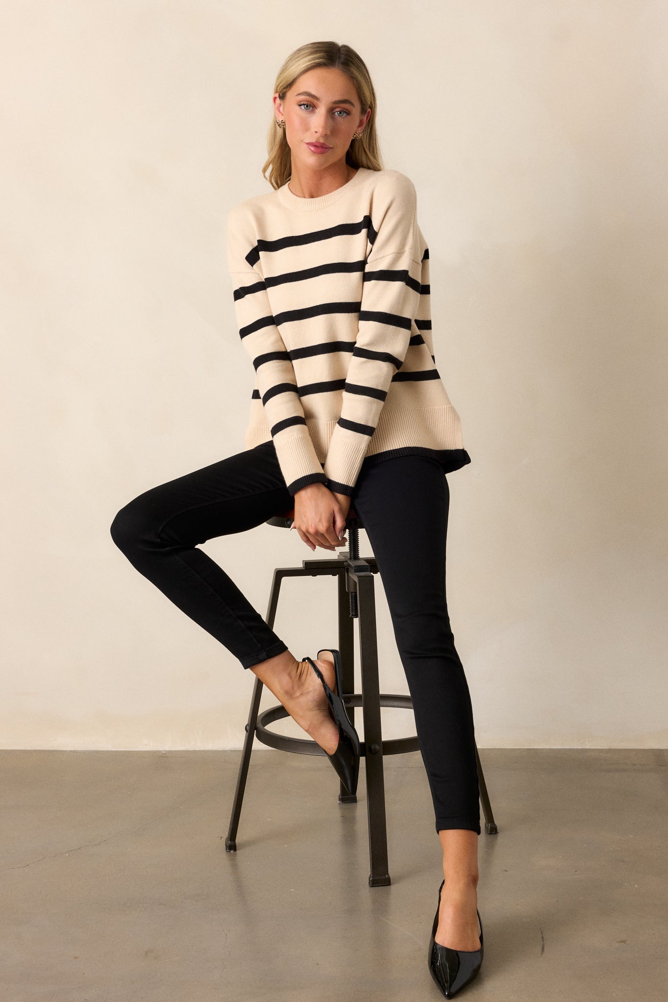 Full-body image highlighting the ribbed cuffs, long sleeves, and the overall relaxed fit of the beige sweater with its stripe design.