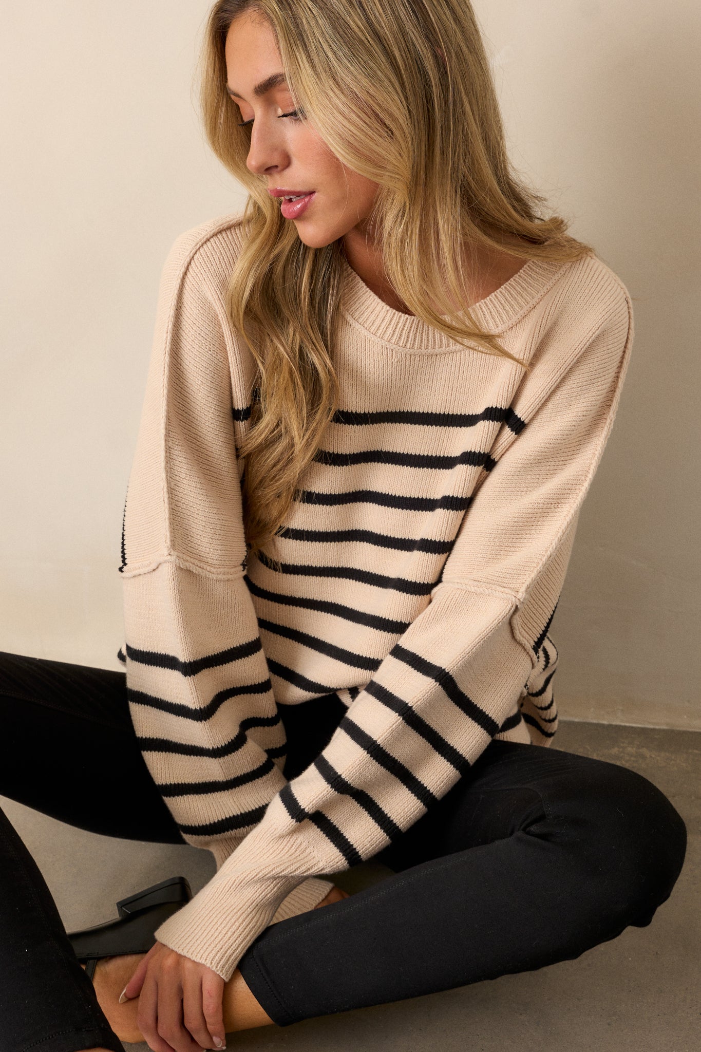 Full-length view of the beige stripe sweater, showcasing its oversized fit and ribbed neckline with the horizontal stripe pattern.