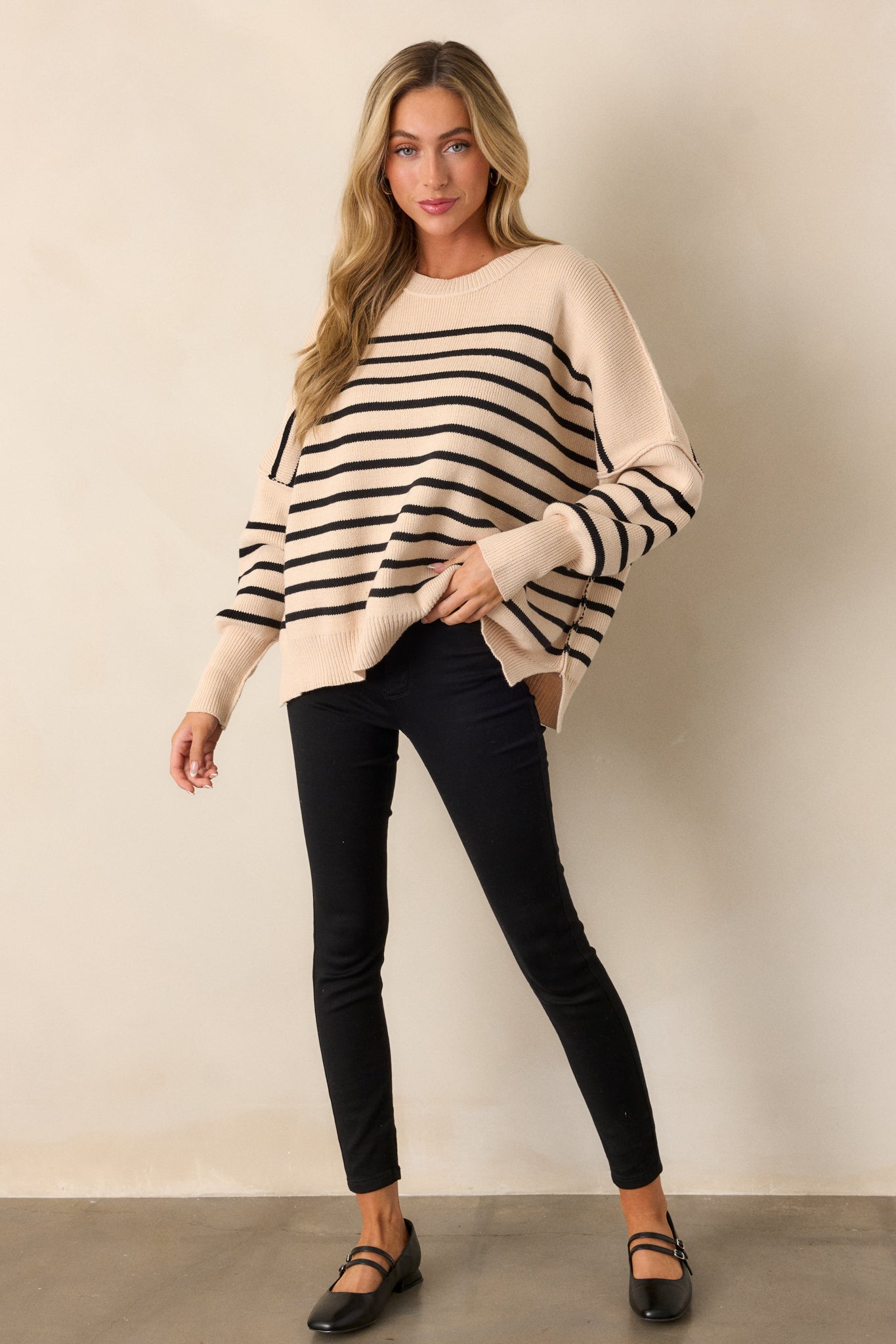 Full-body image highlighting the relaxed, oversized silhouette of the sweater with its ribbed hem and side slits.