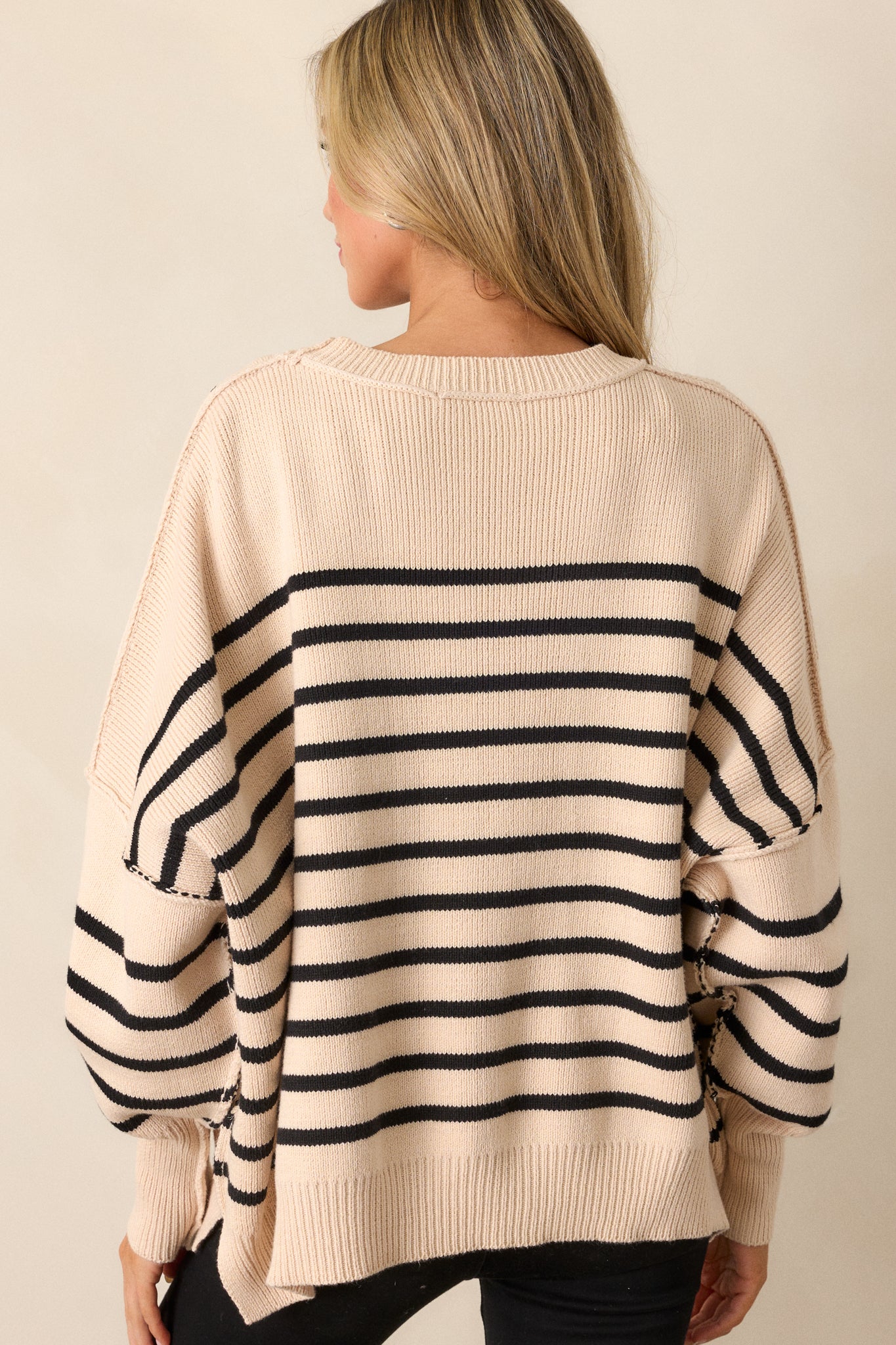 Rear view of the beige sweater, highlighting the oversized fit and horizontal stripes that continue across the back.