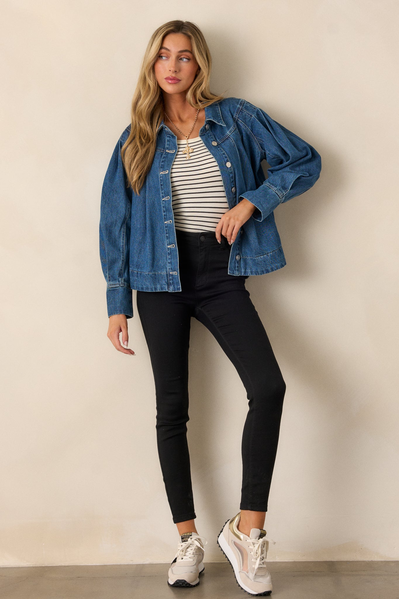 Full-body image highlighting the functional front pockets, silver button detailing, and dark wash denim texture of the jacket.