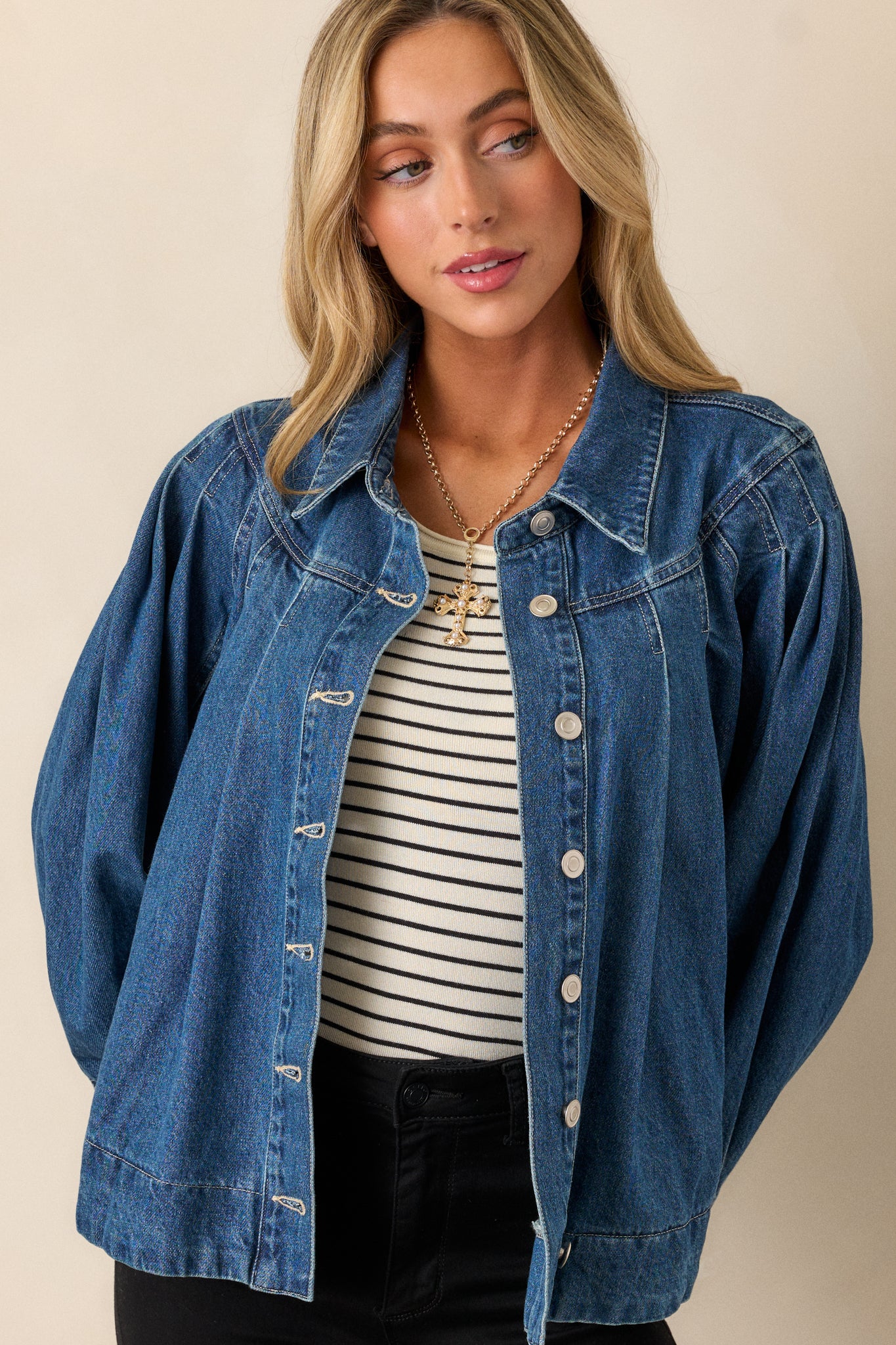 Close-up of the buttoned front of the jacket, highlighting the silver buttons and dark wash denim fabric.