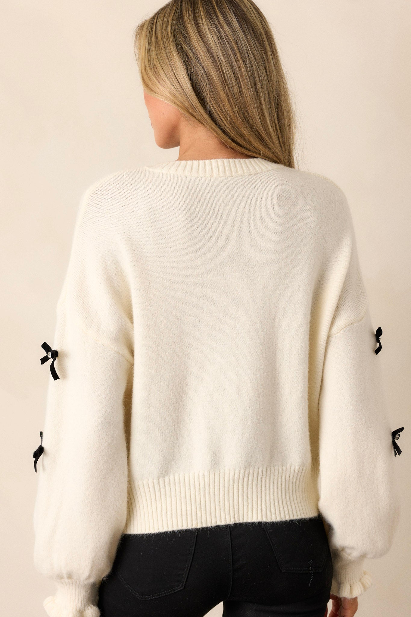 A view of the back of the ivory sweater, highlighting the clean lines and the continuation of the ribbed texture without any visible bows.