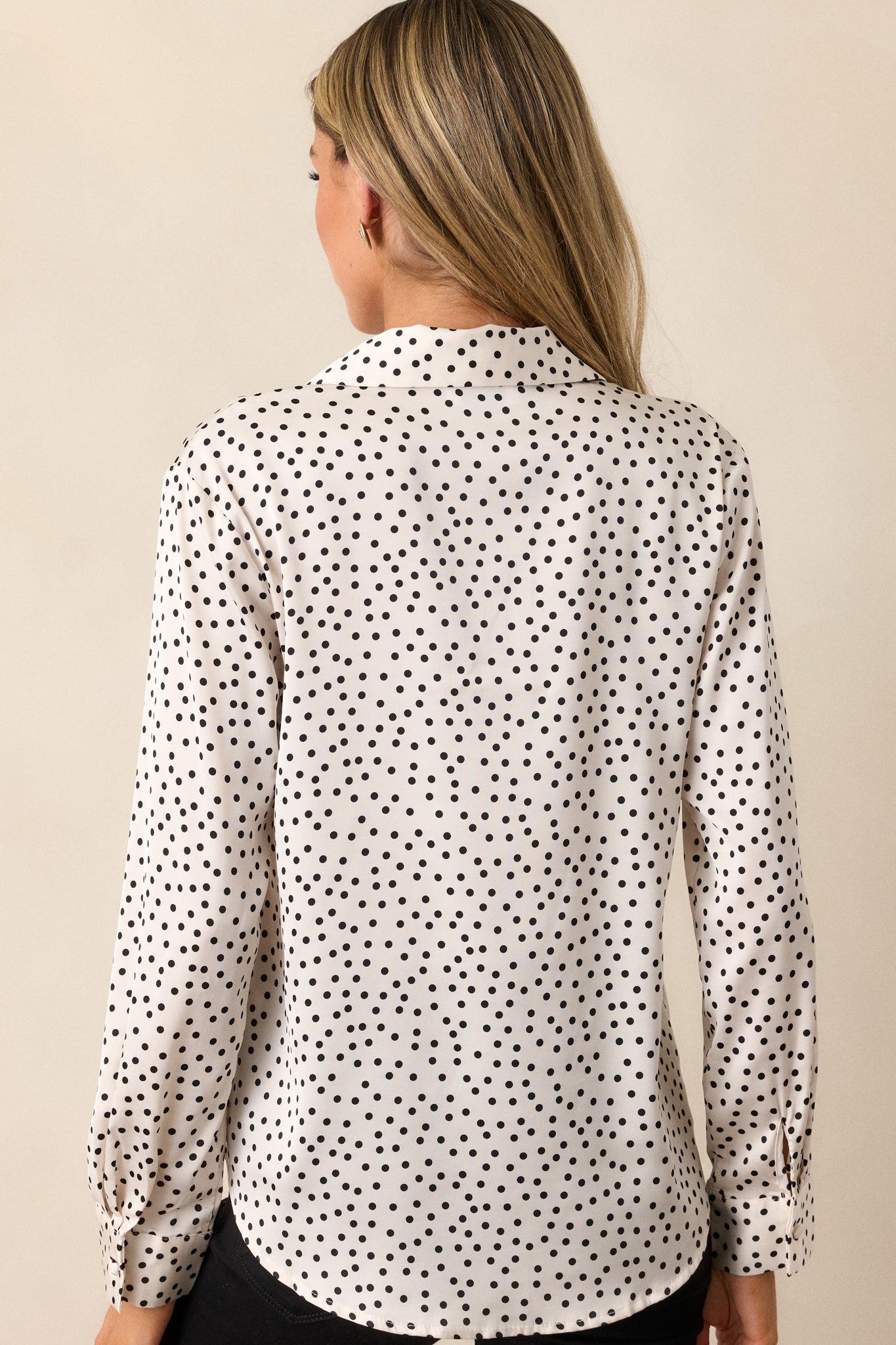 Rear view of the polka dot top, highlighting the cuffed sleeves and the smooth finish of the fabric, with the collar visible.