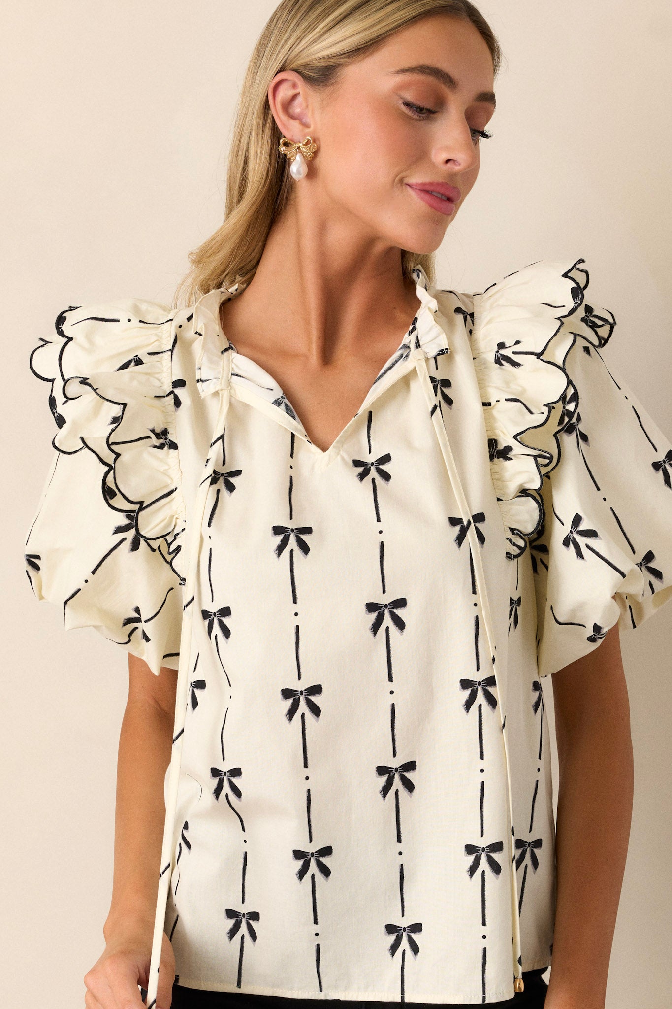 A front full-length image focusing on the overall fit of the top, with emphasis on the black bow print and the split v-neckline.