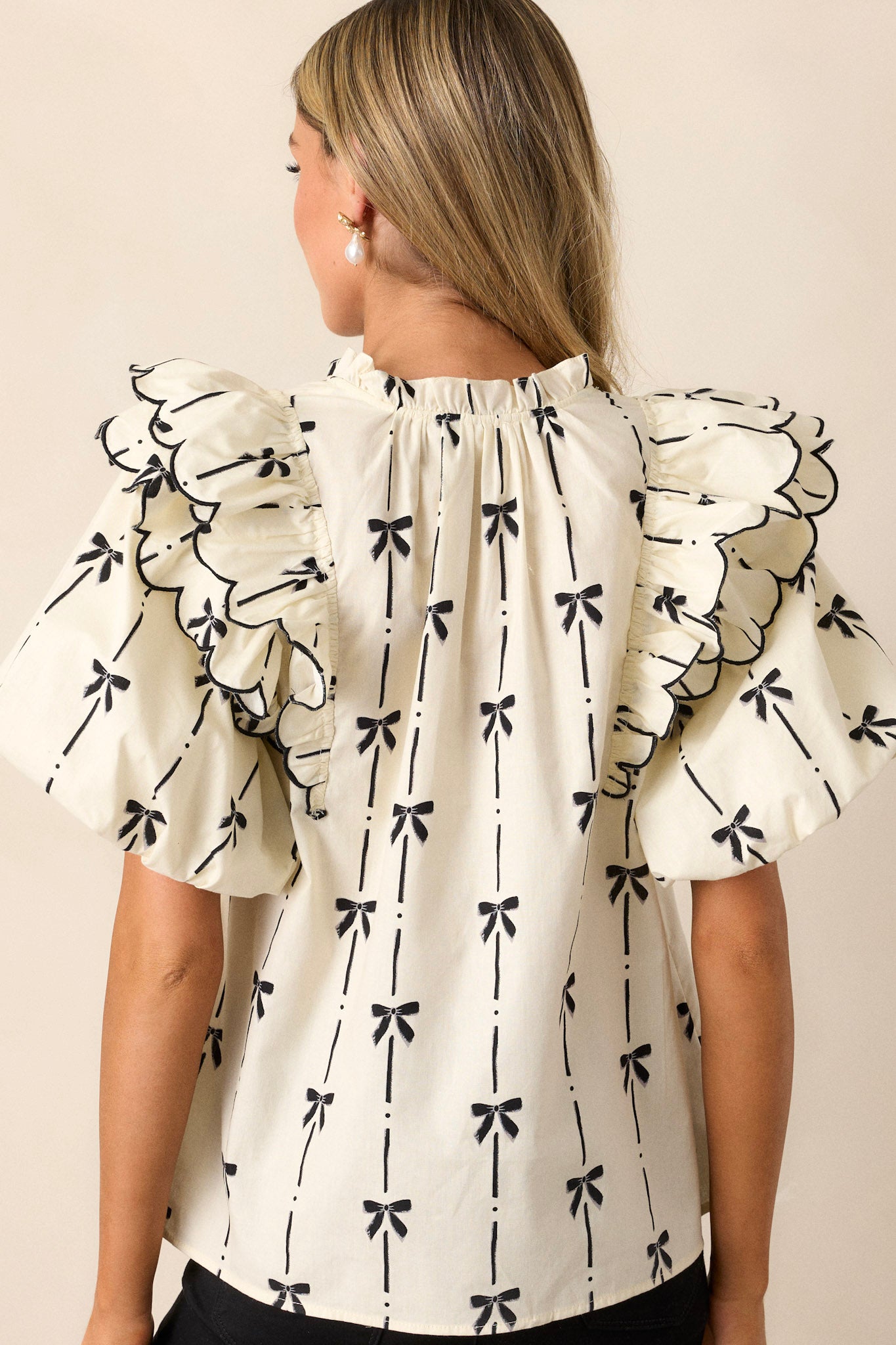 A back view of the top, displaying the placement of the black bow print across the back and the flow of the fabric without visible ruffle detailing.