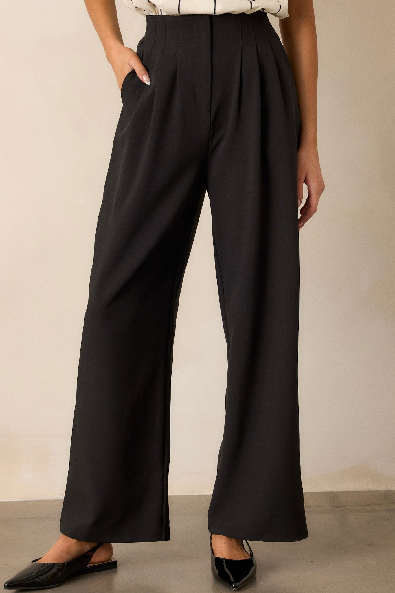 Front angled view of black straight leg pants featuring a high waisted design, slight pleats, functional hip pockets, and a straight leg cut