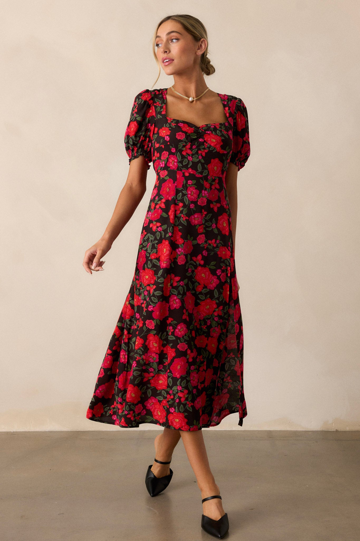 A frontal view of the black floral dress, showcasing the square neckline, with the vibrant pink and red floral print prominently displayed across the bodice and skirt. 