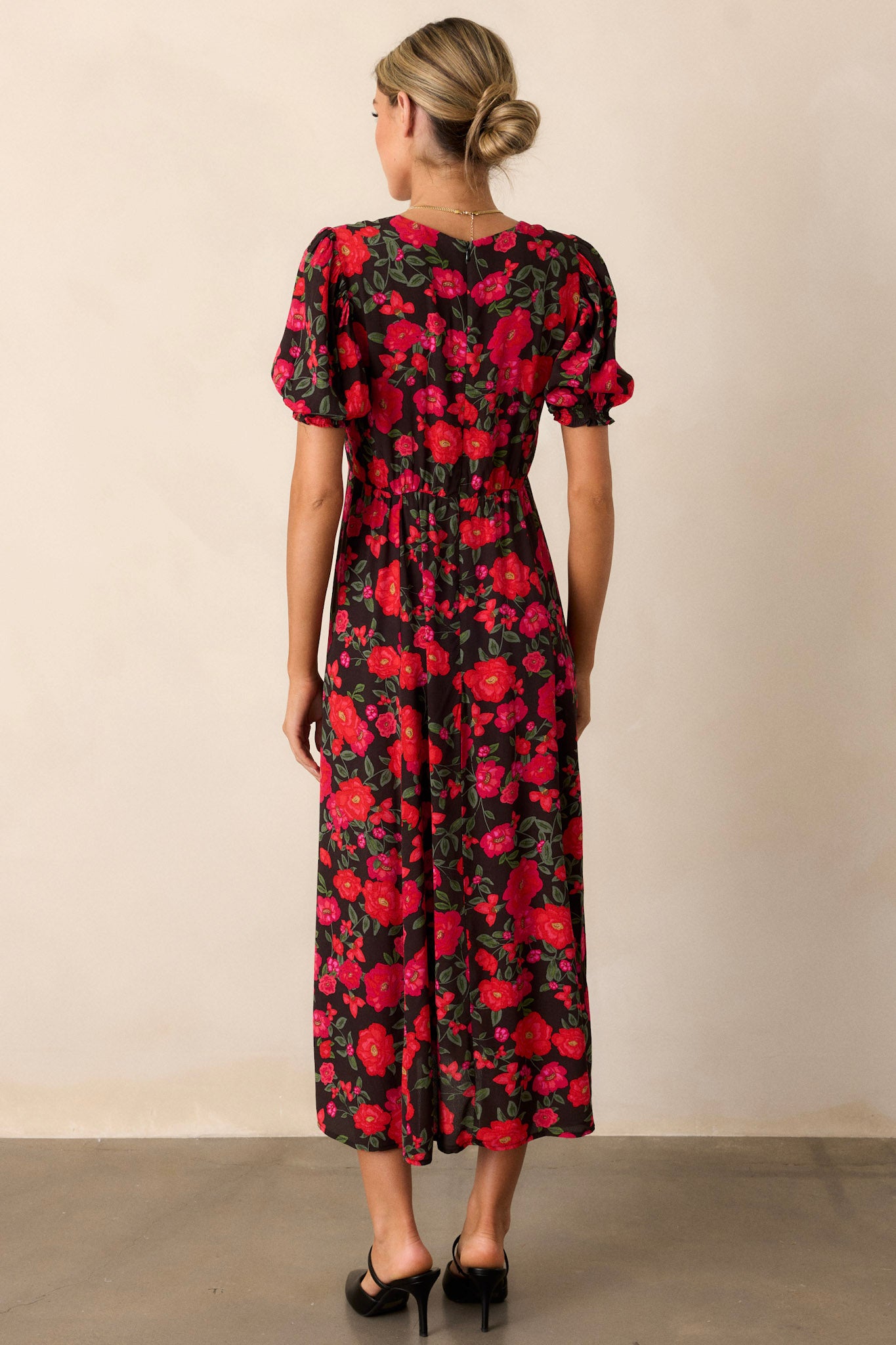 A view of the back of the black floral dress, emphasizing the discreet back zipper and the continuity of the floral design.