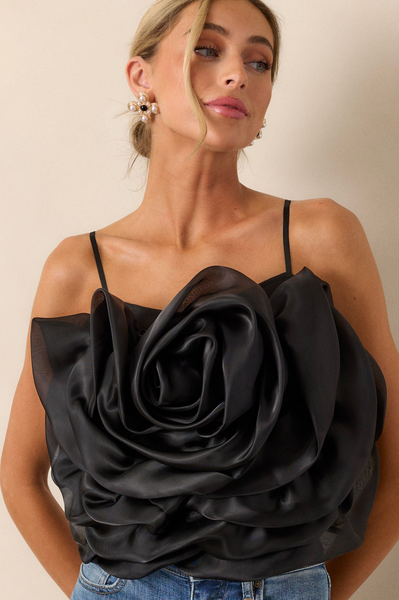 This black crop top features a square neckline, thin & stretchy adjustable straps, a fully smocked back, a large 3-D flower, and a cropped hemline.