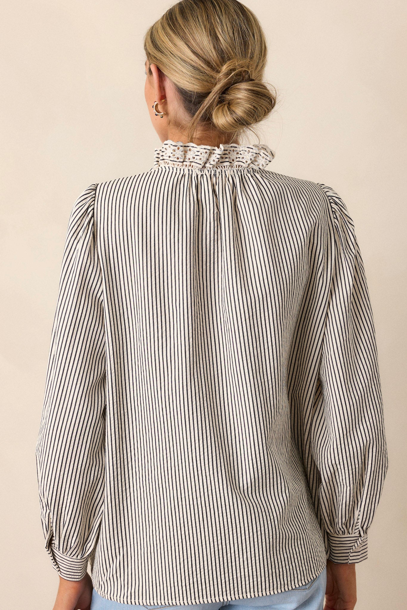 Back view of this navy stripe top that features a lace collar, a functional button front bust, a vertical stripe pattern, navy and ivory stripes and puffed long sleeves.