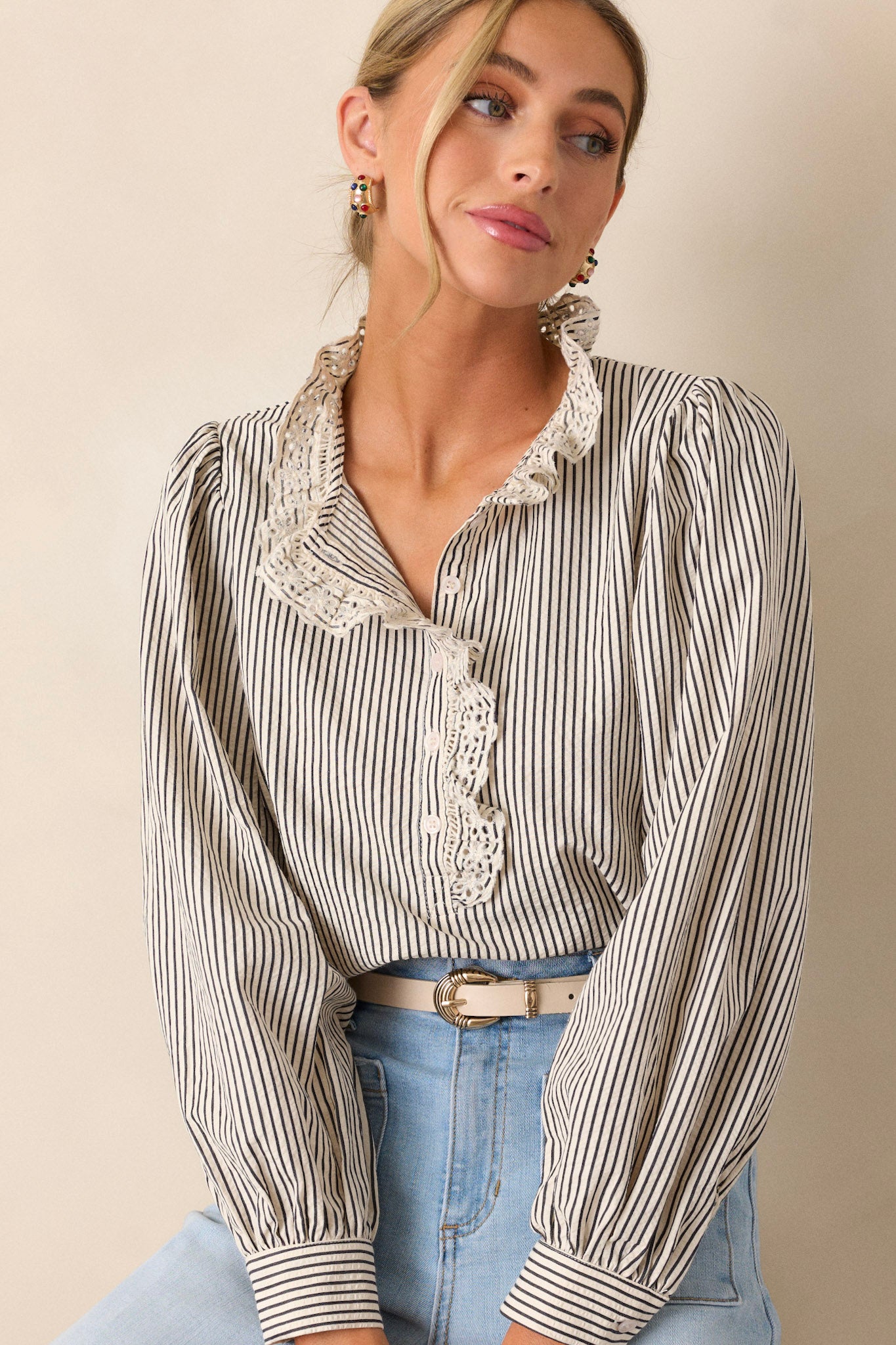 Side view of this navy stripe top that features a lace collar, a functional button front bust, a vertical stripe pattern, navy and ivory stripes and puffed long sleeves.
