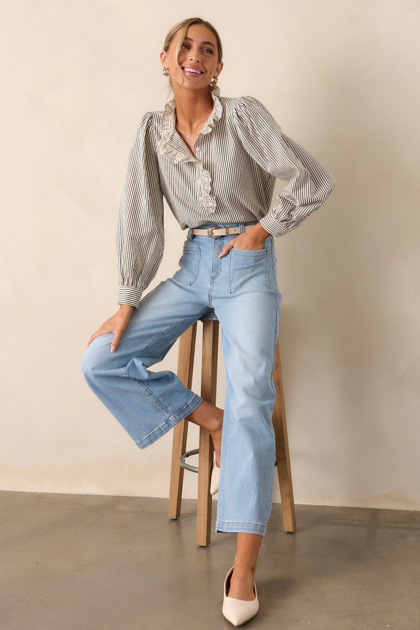 Front angled view of this navy stripe top that features a lace collar, a functional button front bust, a vertical stripe pattern, navy and ivory stripes and puffed long sleeves.