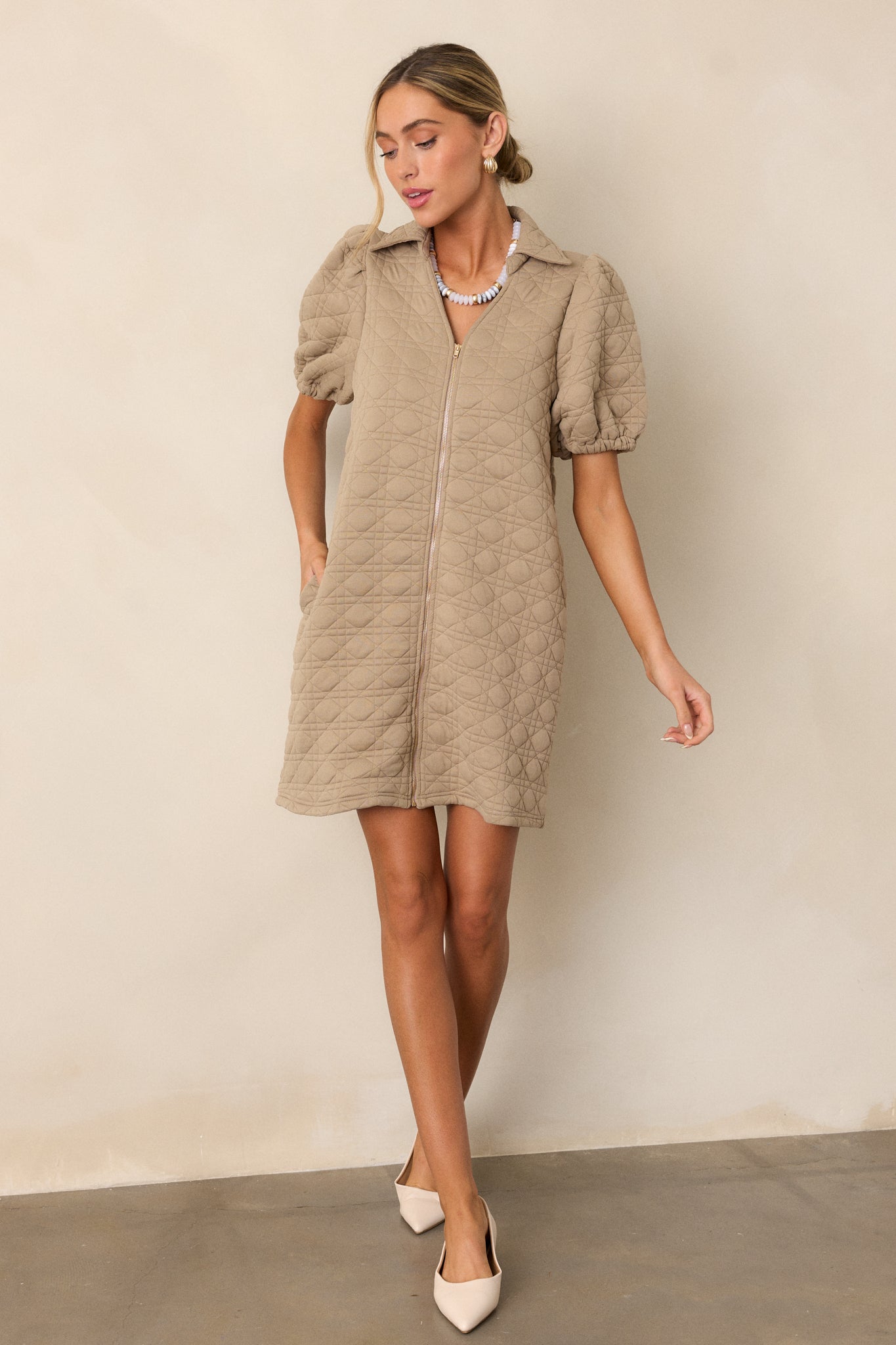 A tan mini dress with a functional full-zip front, featuring short puff sleeves, a collared neckline, and quilted fabric.