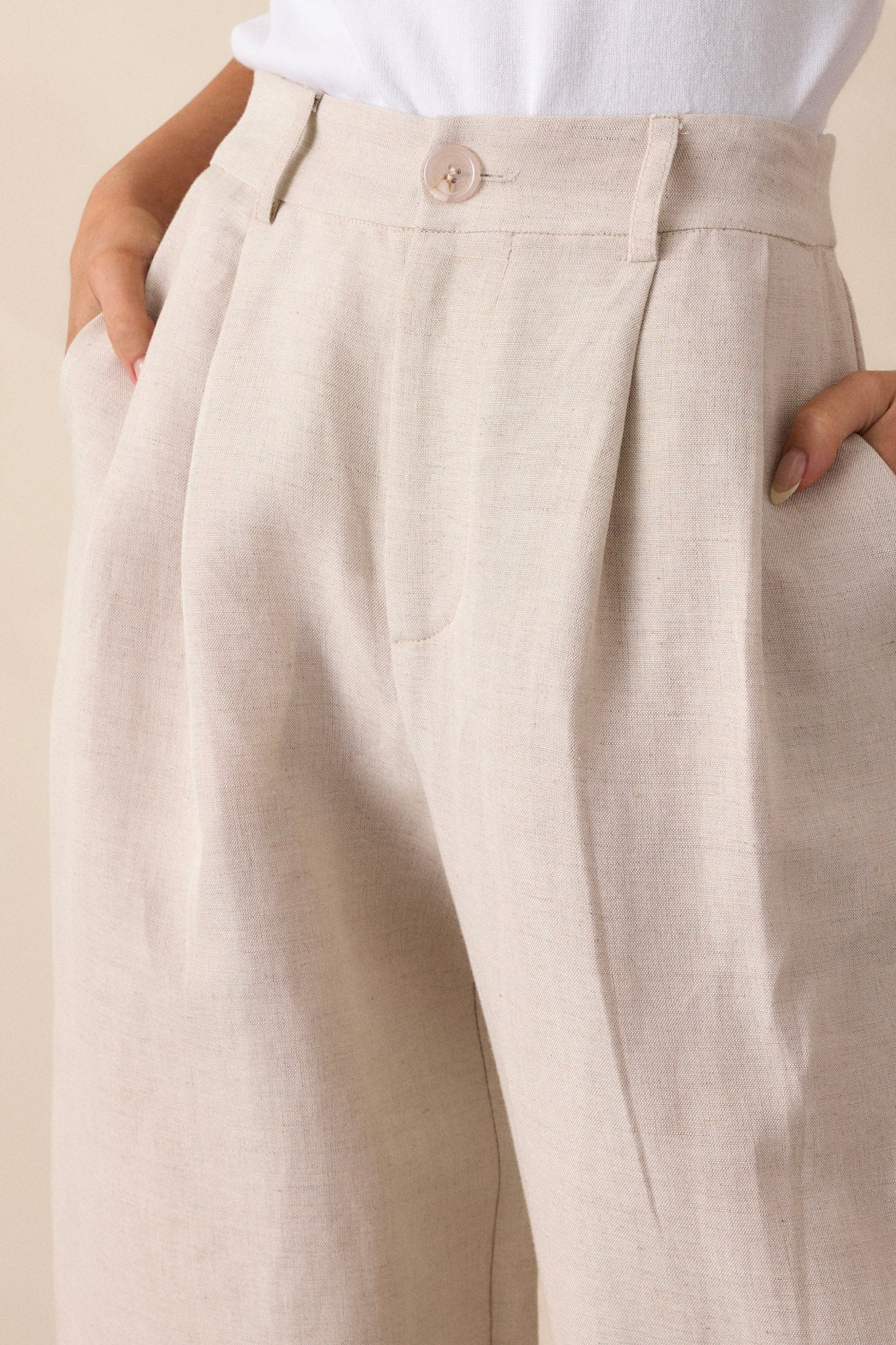 Close-up of the beige straight leg pants showing the high waisted design, functional belt loops, slight pleats, and functional hip pockets.