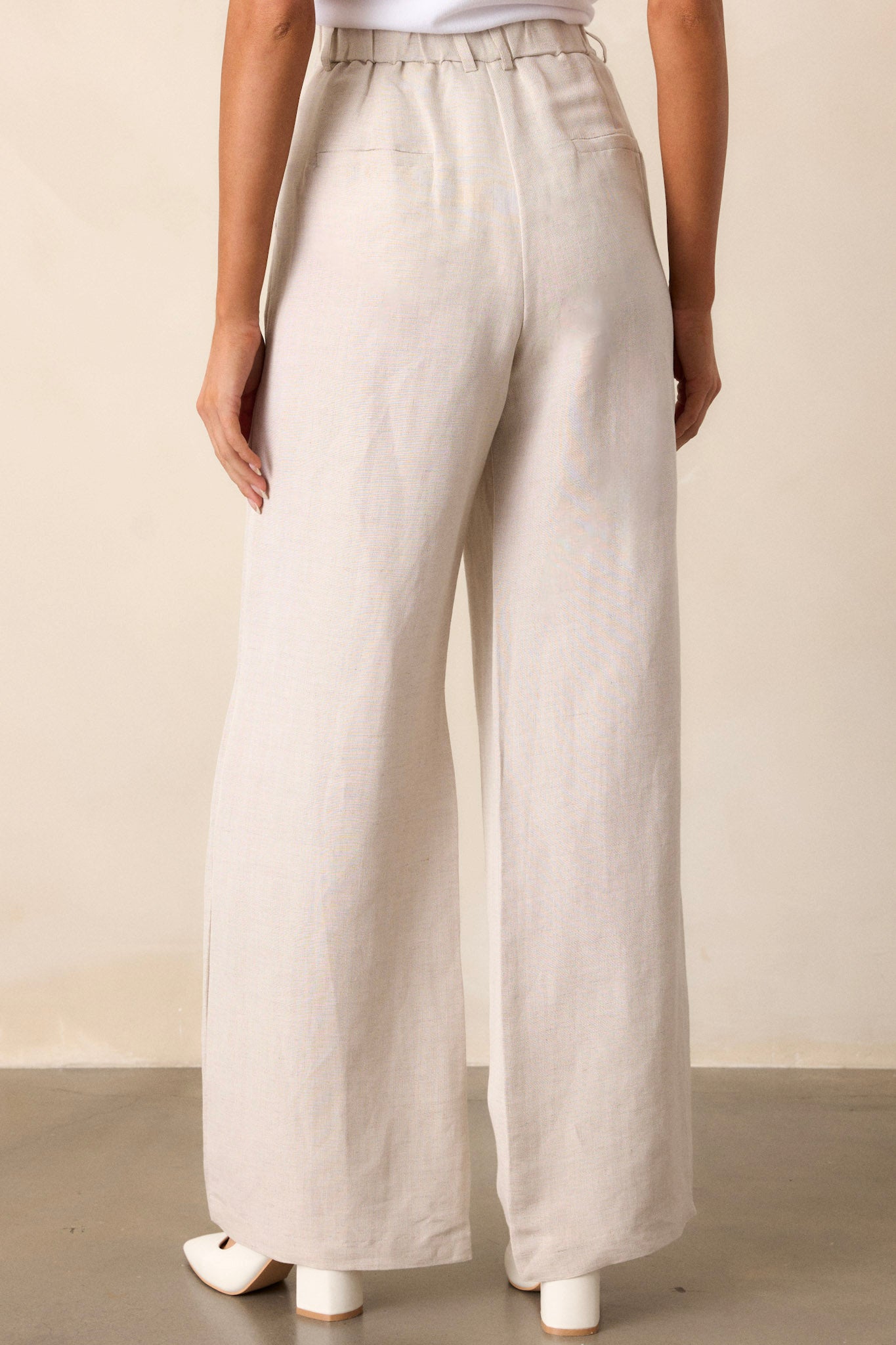 Back view of beige straight leg pants highlighting the overall fit, high waisted design, and the straight leg cut.