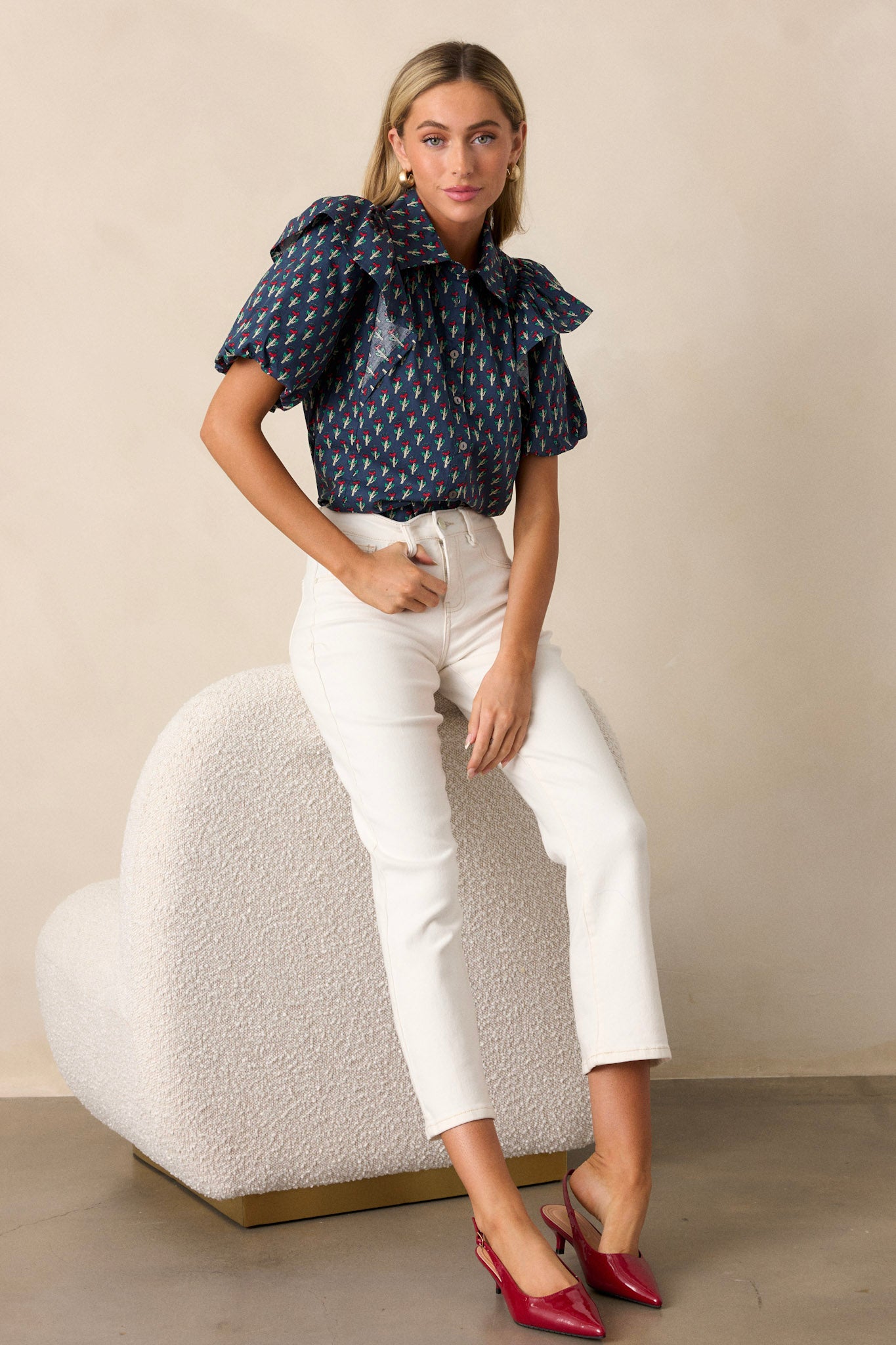 Navy top with an all-over red and green floral print, elastic puff sleeves, and a collared neckline, showing a flattering fit and flare silhouette.