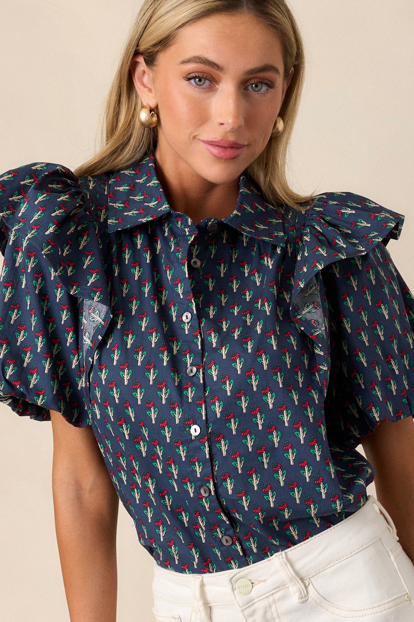 Close-up of the collared neckline and button front of the navy top, highlighting the floral print and neat button details.