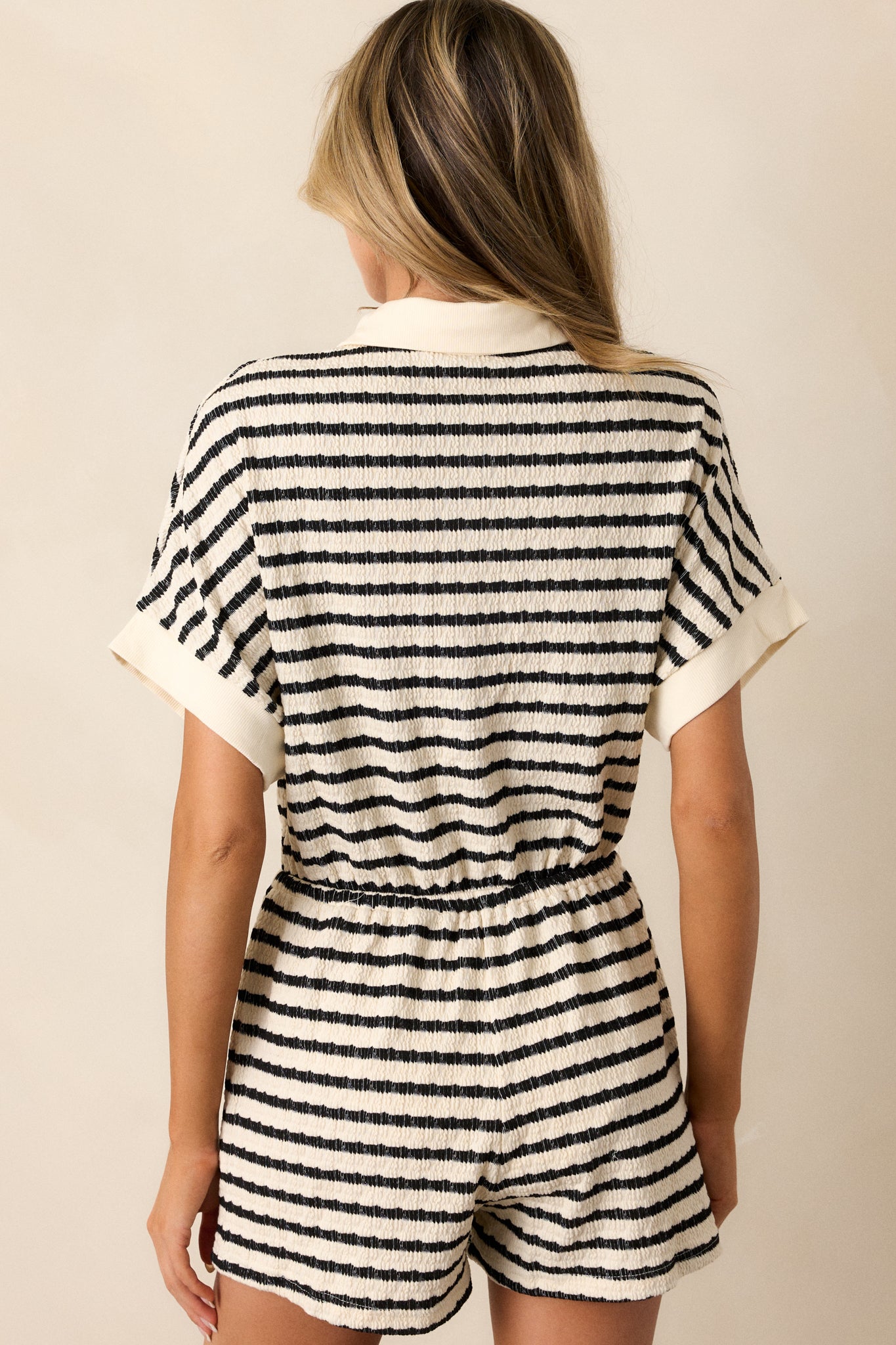 Back view of the striped romper, showcasing the wide short sleeves and the overall design, with the textured material clearly visible.