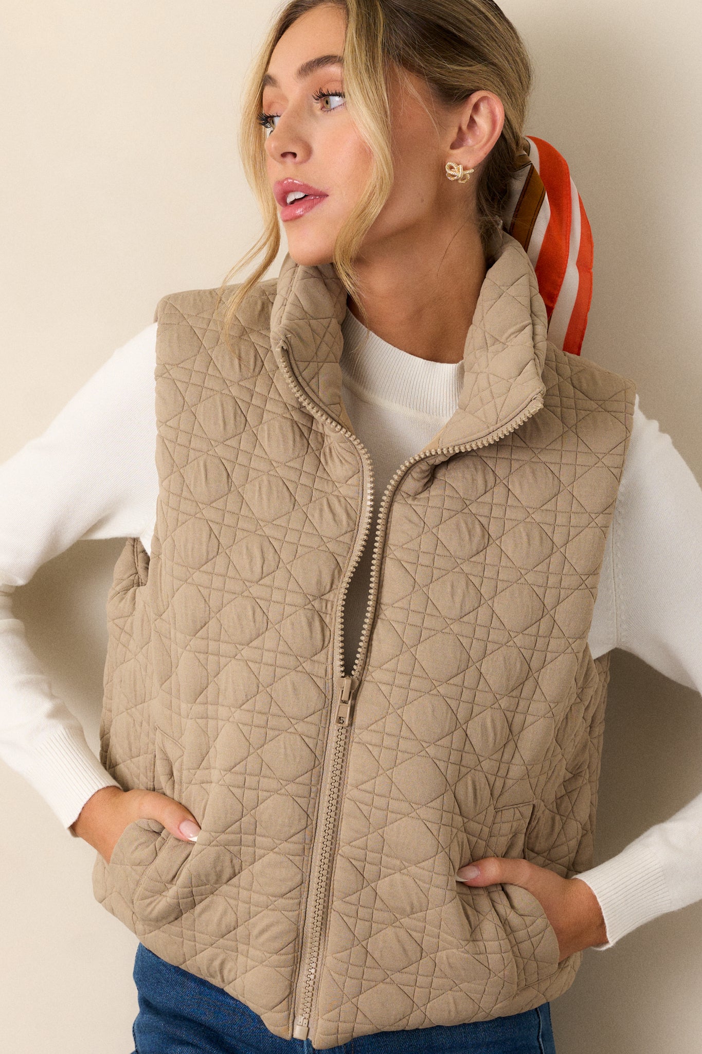 Front view of a tan vest featuring a stylish quilted design, a full zip closure, a collared neckline, and functional pockets.