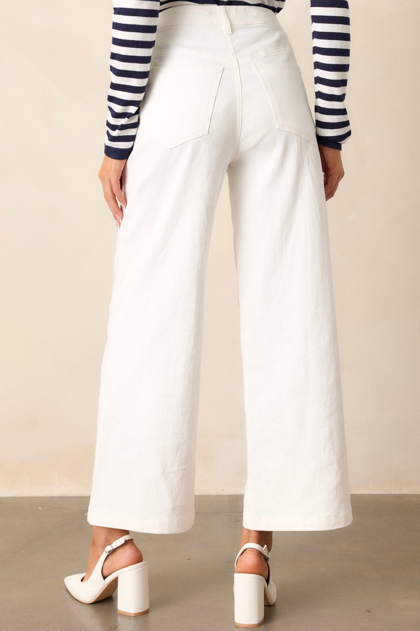 Back view of ivory jeans highlighting the high waisted design, belt loops, functional back pockets, and wide leg design.