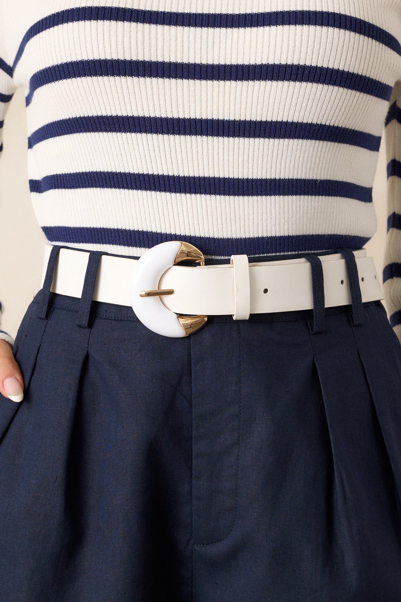 This white belt features gold hardware, faux lather and multiple belt holes for adjusting.