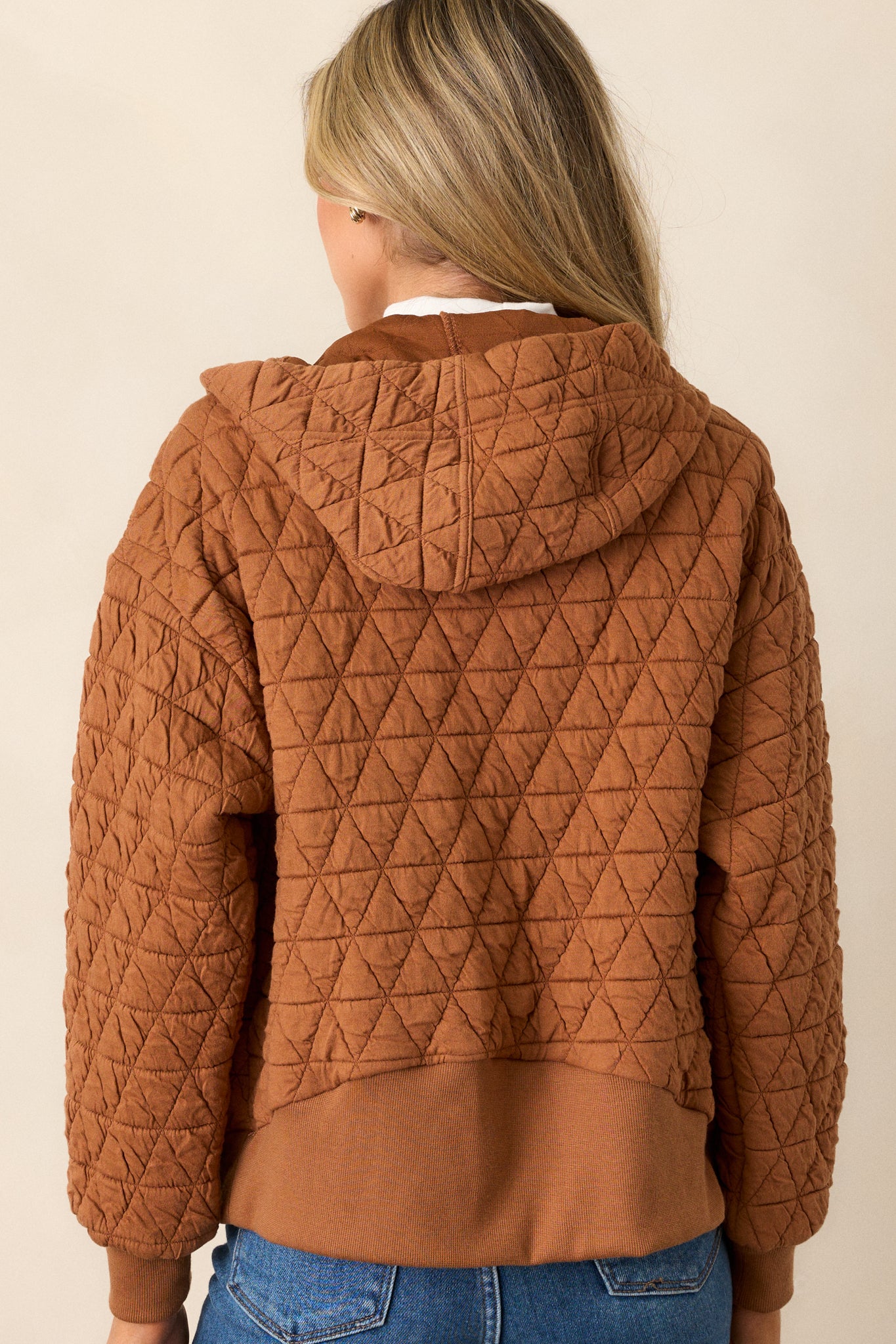 Back view of the copper quilted jacket highlighting the thick hem, quilted design, and cuffed long sleeves.