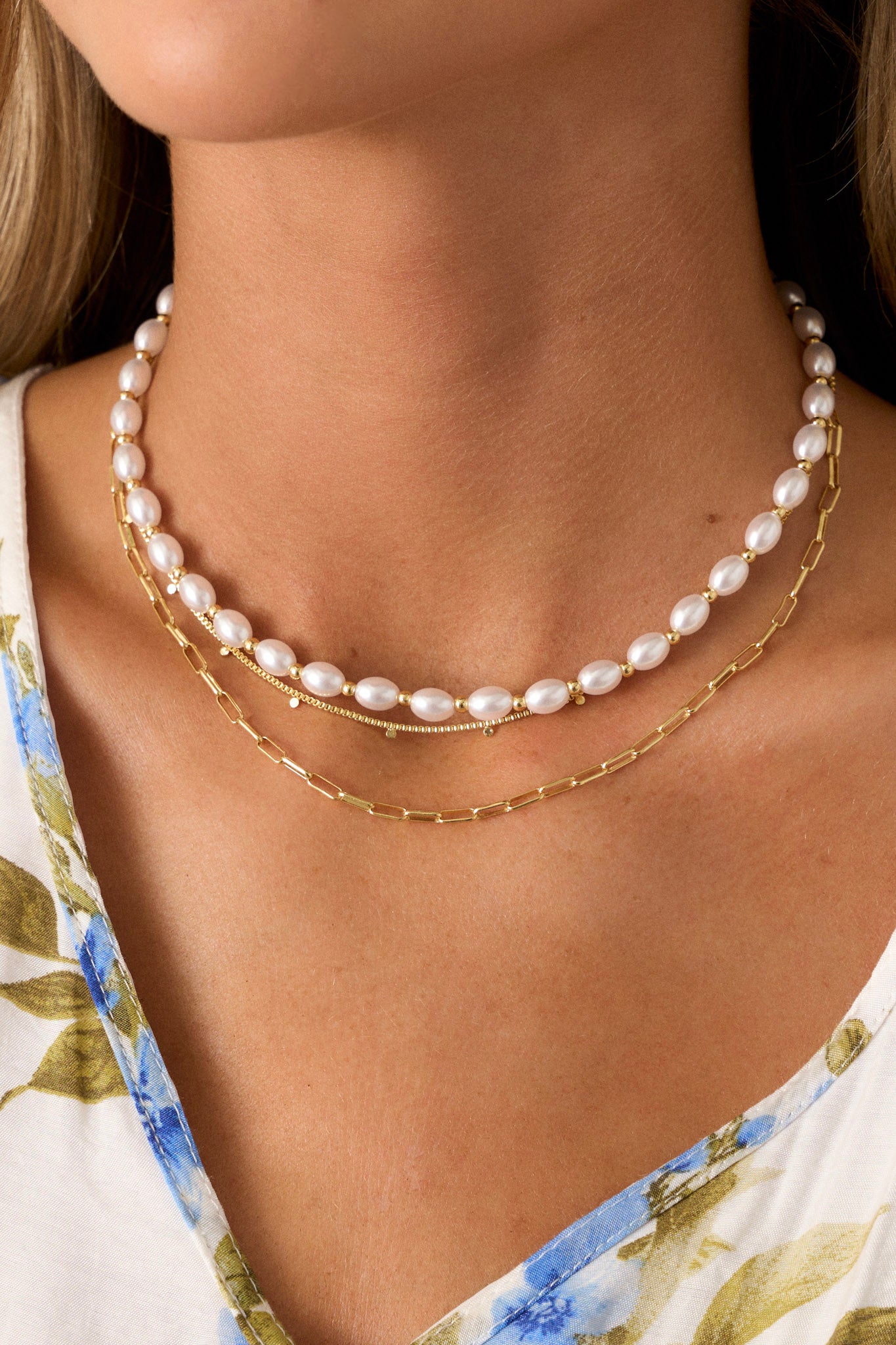 A detailed view of the necklace, showing the layered thin gold chain with small accent gold circles and the delicate faux pearl chain.