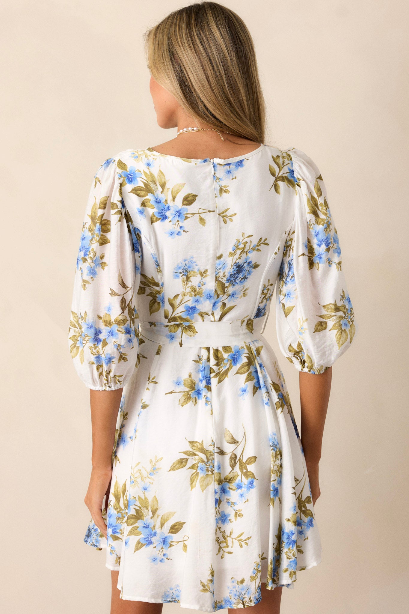 Back view of this blue & white floral dress, featuring puff sleeves and a tied waist, highlighting the floral pattern on the back.