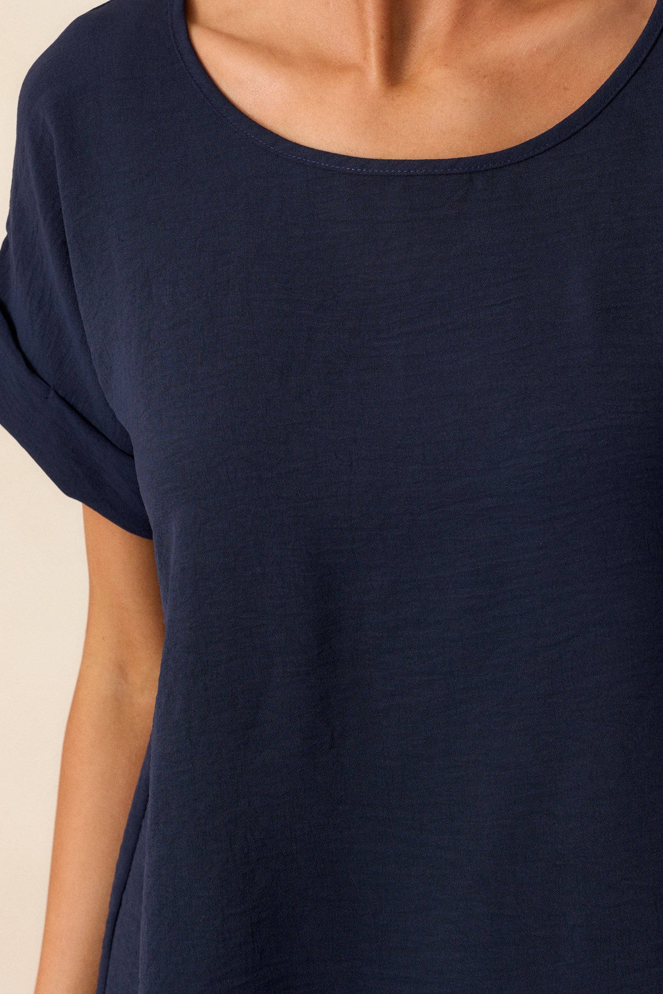 A close-up of the crew neckline, focusing on the precise stitching and how the neckline sits flat against the collarbone.